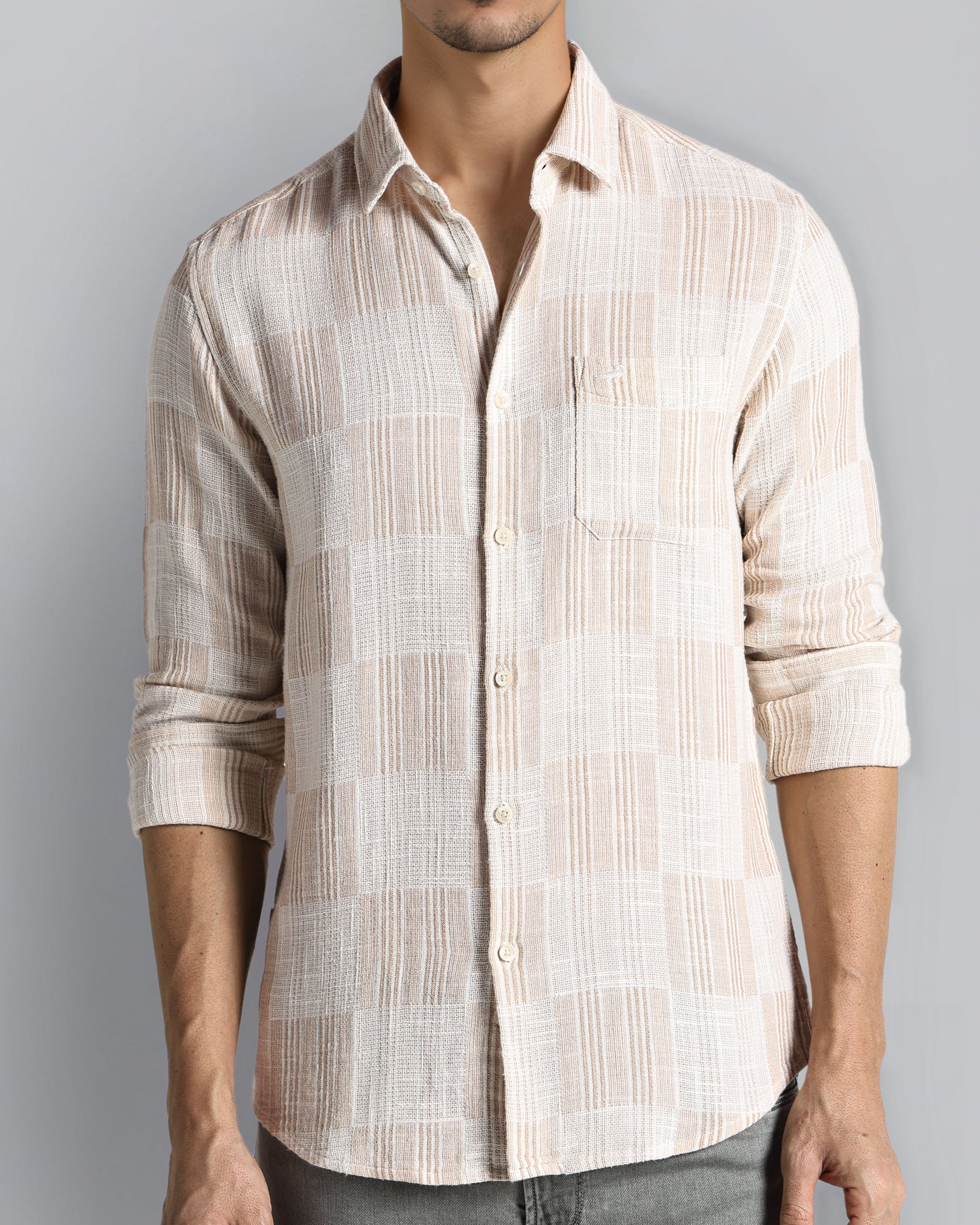 Man wearing a beige striped shirt against a gray background