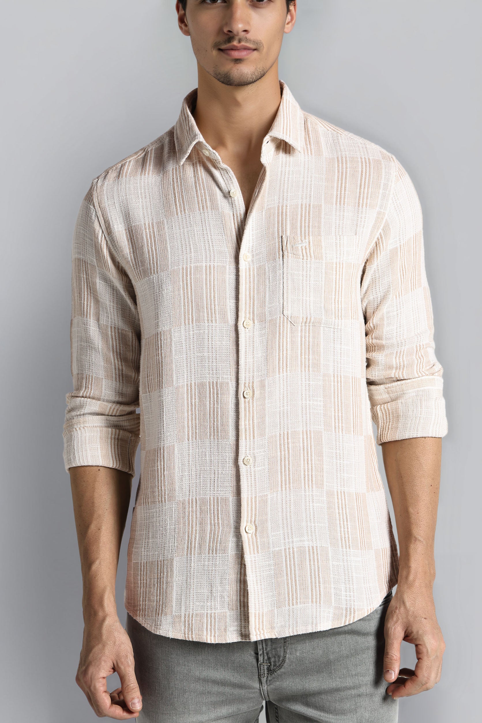Man wearing a beige striped shirt against a gray background