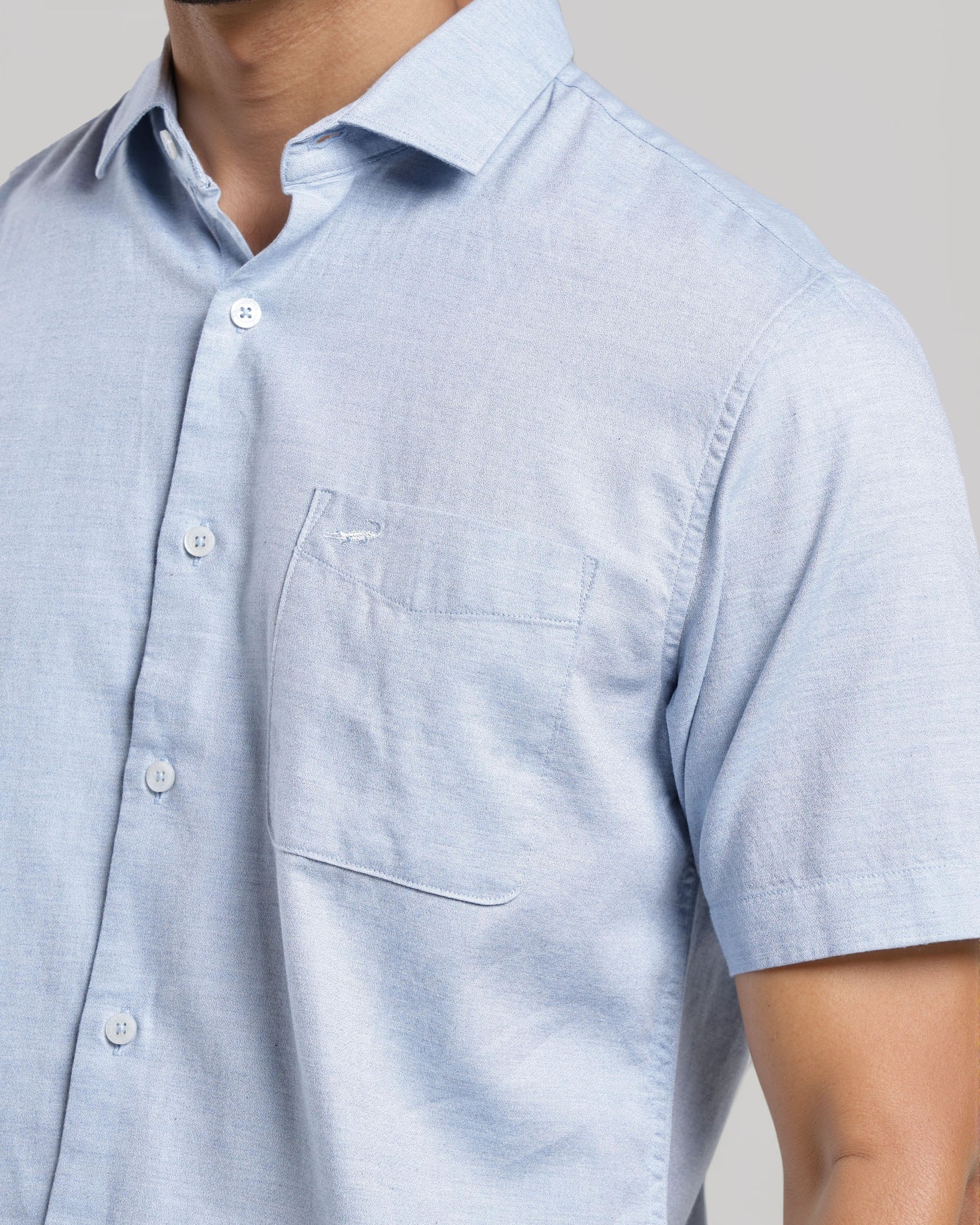 Light blue short-sleeve shirt worn by a person on a neutral background