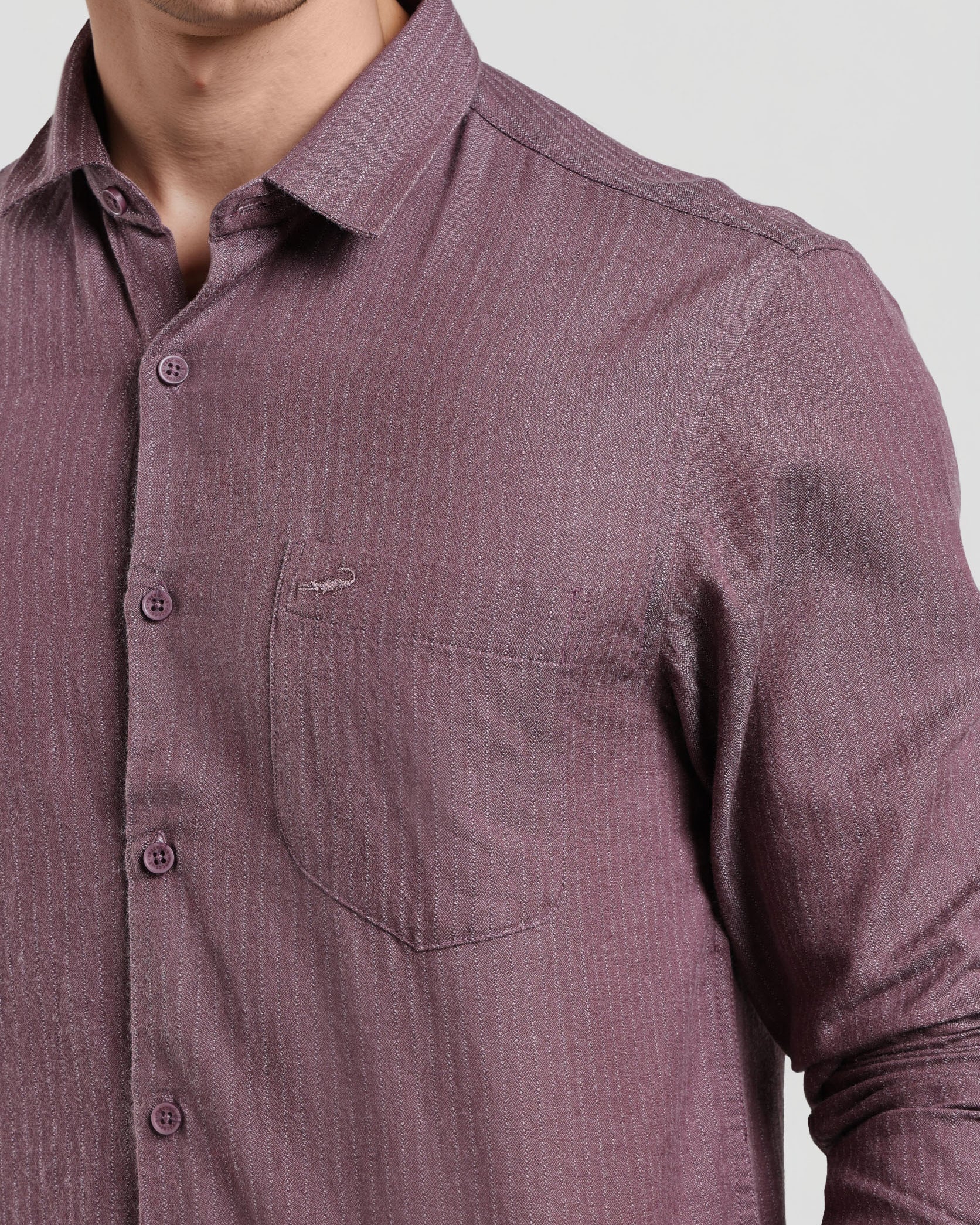 Close-up of a purple button-up shirt with a pocket on a light gray background