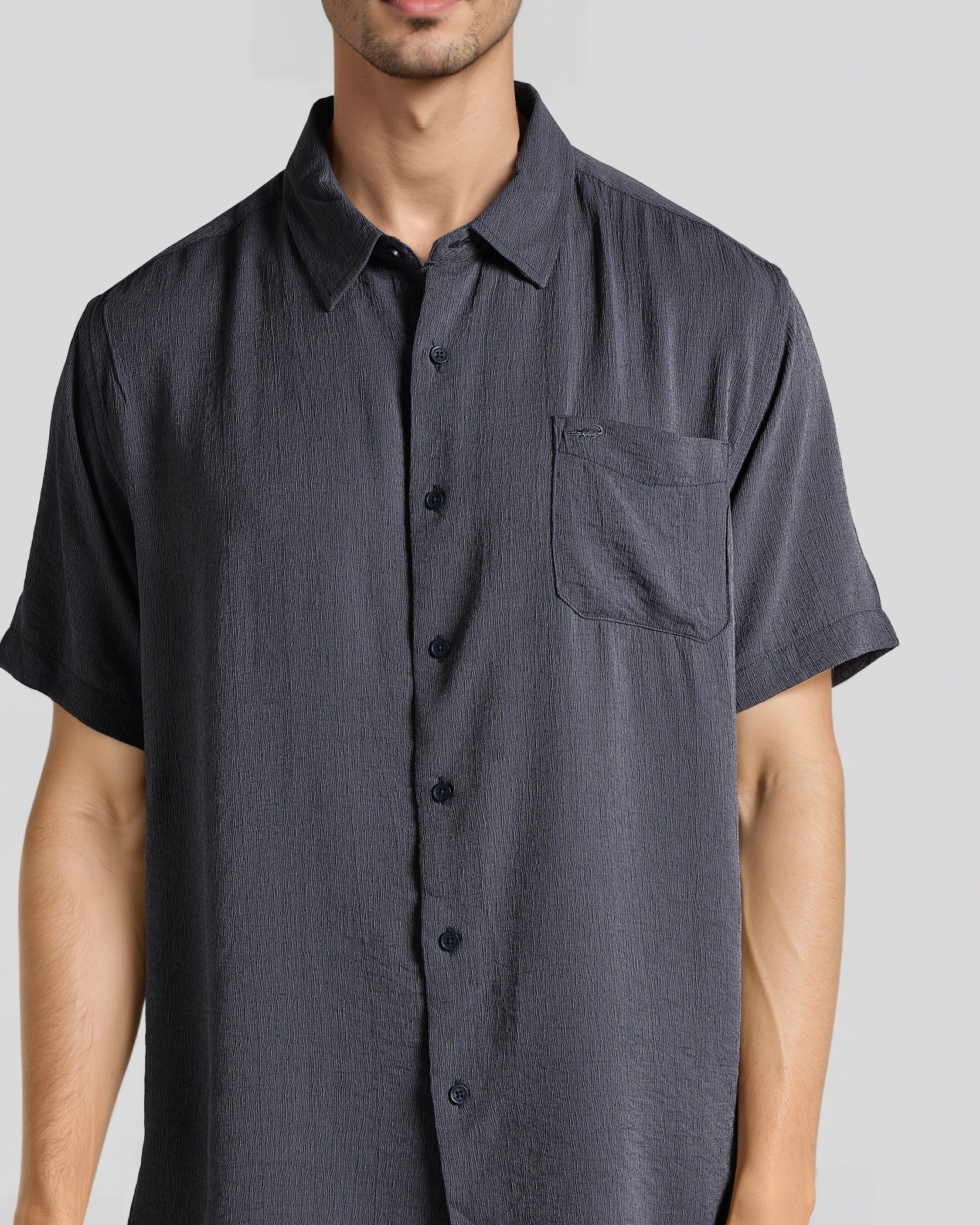 Man wearing a dark gray short-sleeve button-up shirt on a light gray background