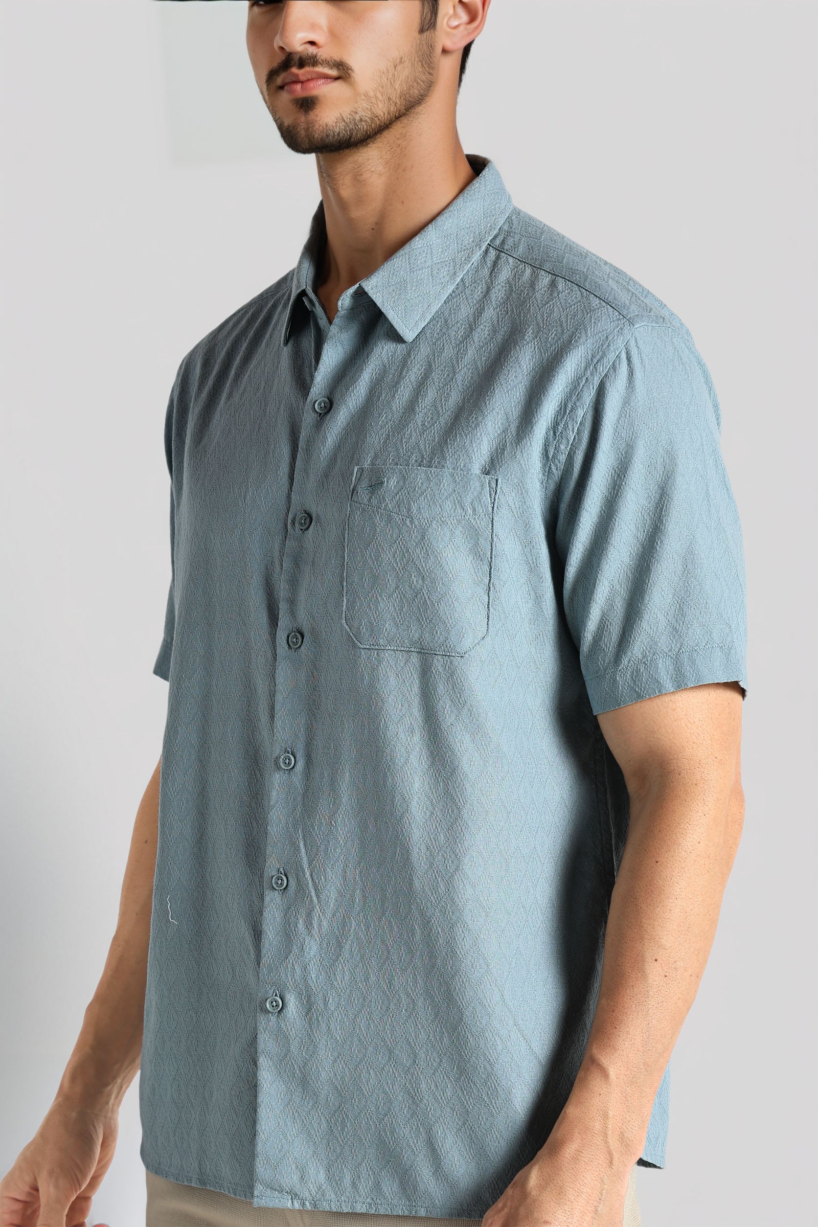 Man wearing a light blue short-sleeve button-up shirt against a plain background