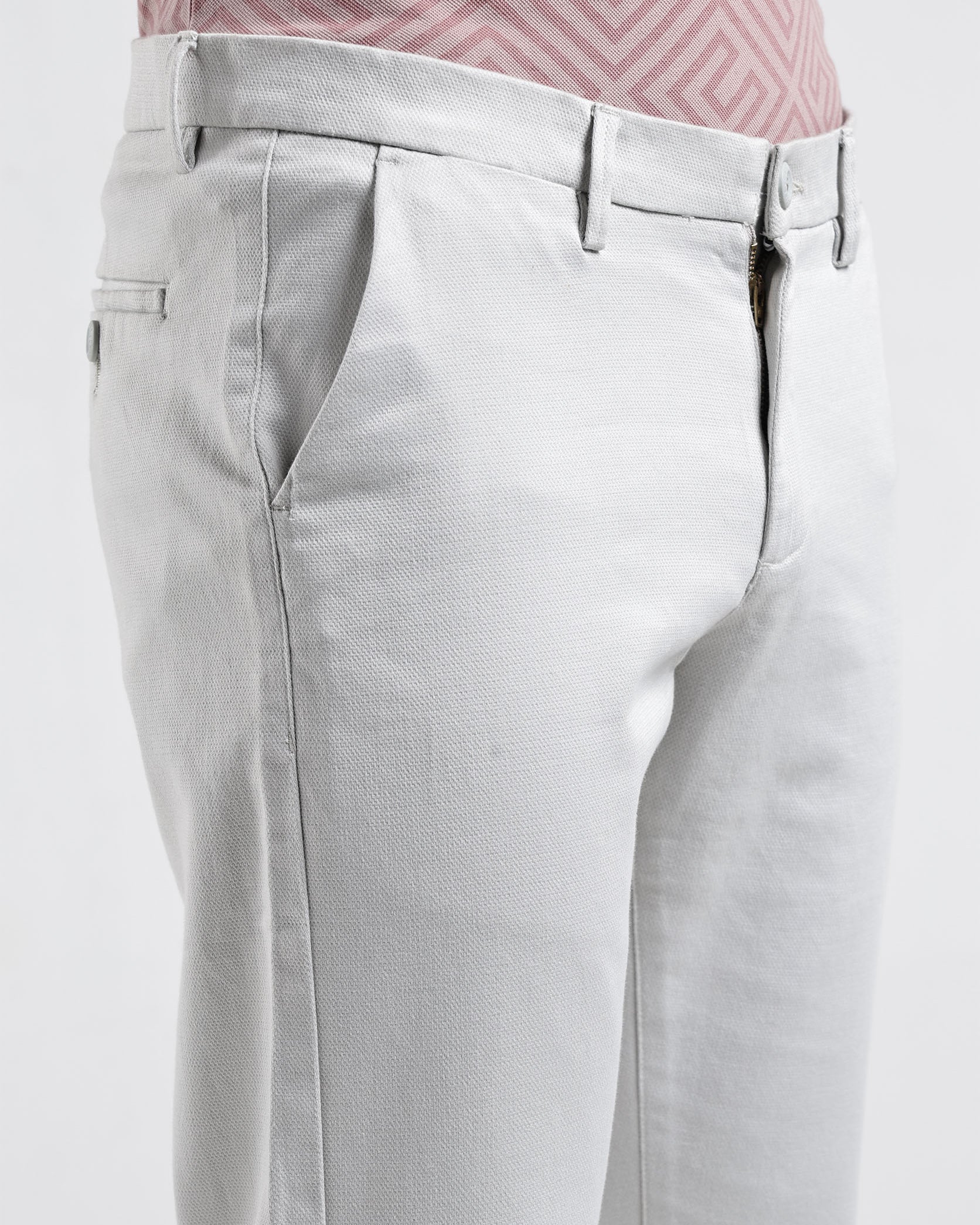 Light gray pants worn with a pink patterned shirt on a white background