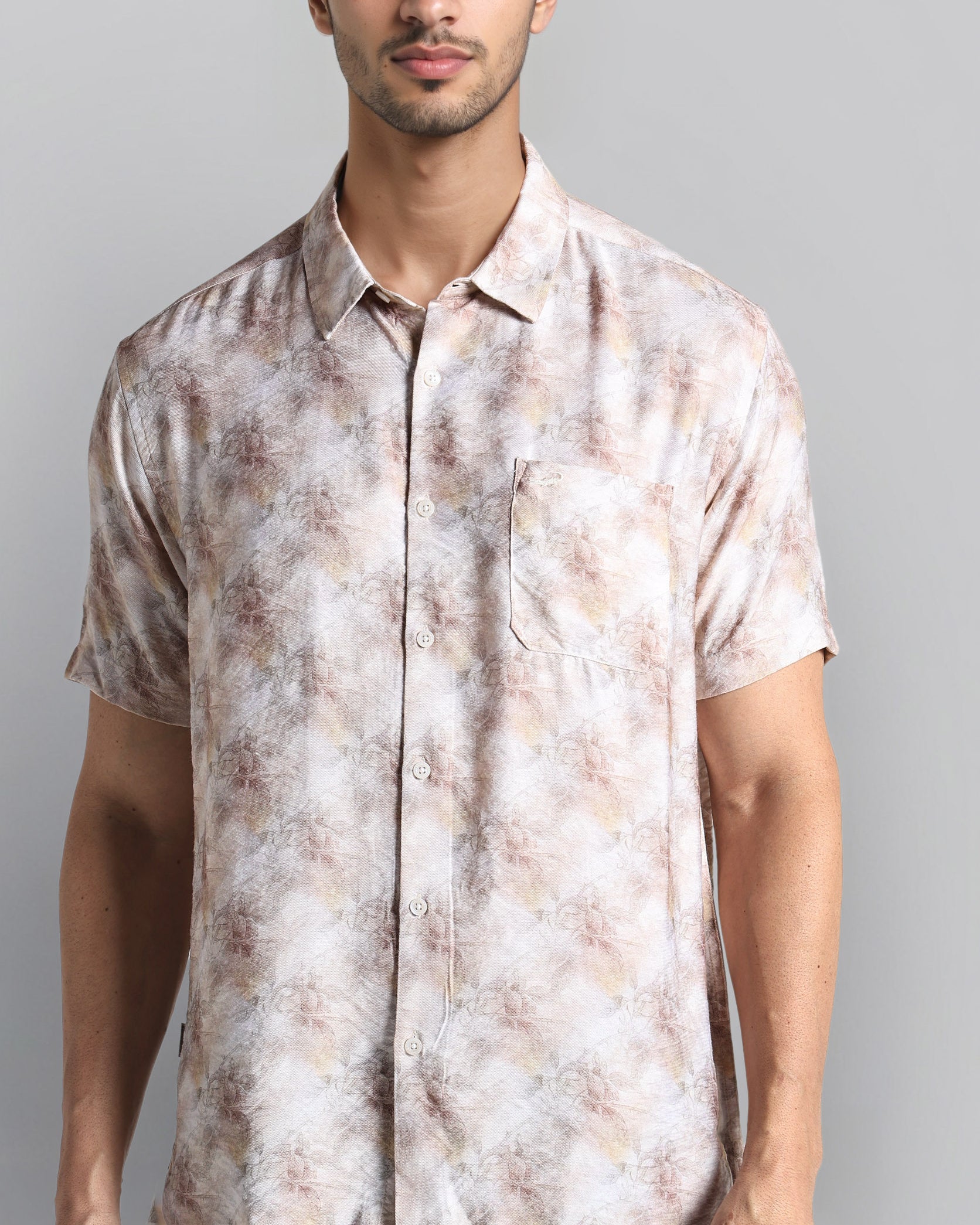 Man wearing a patterned shirt against a gray background