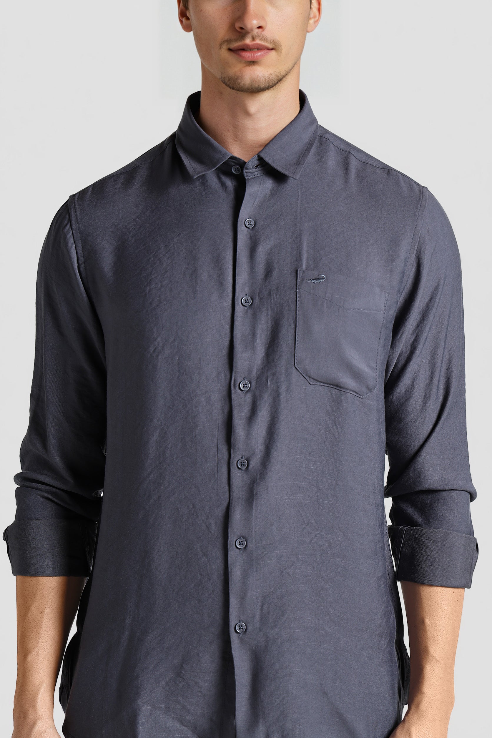 Man wearing a dark gray button-up shirt on a light gray background