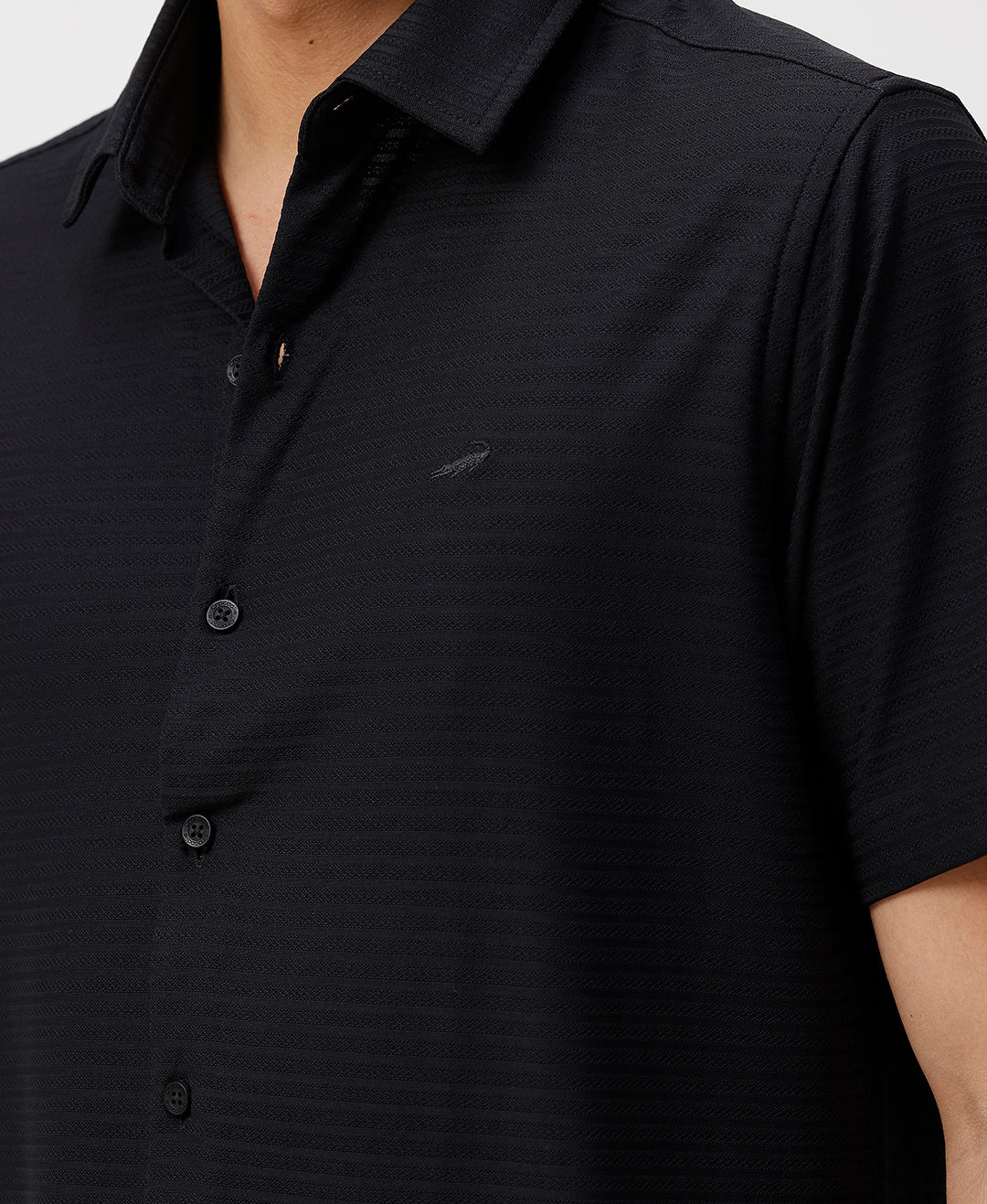 Man wearing a black solid black cotton shirt with casual styling on a gray background