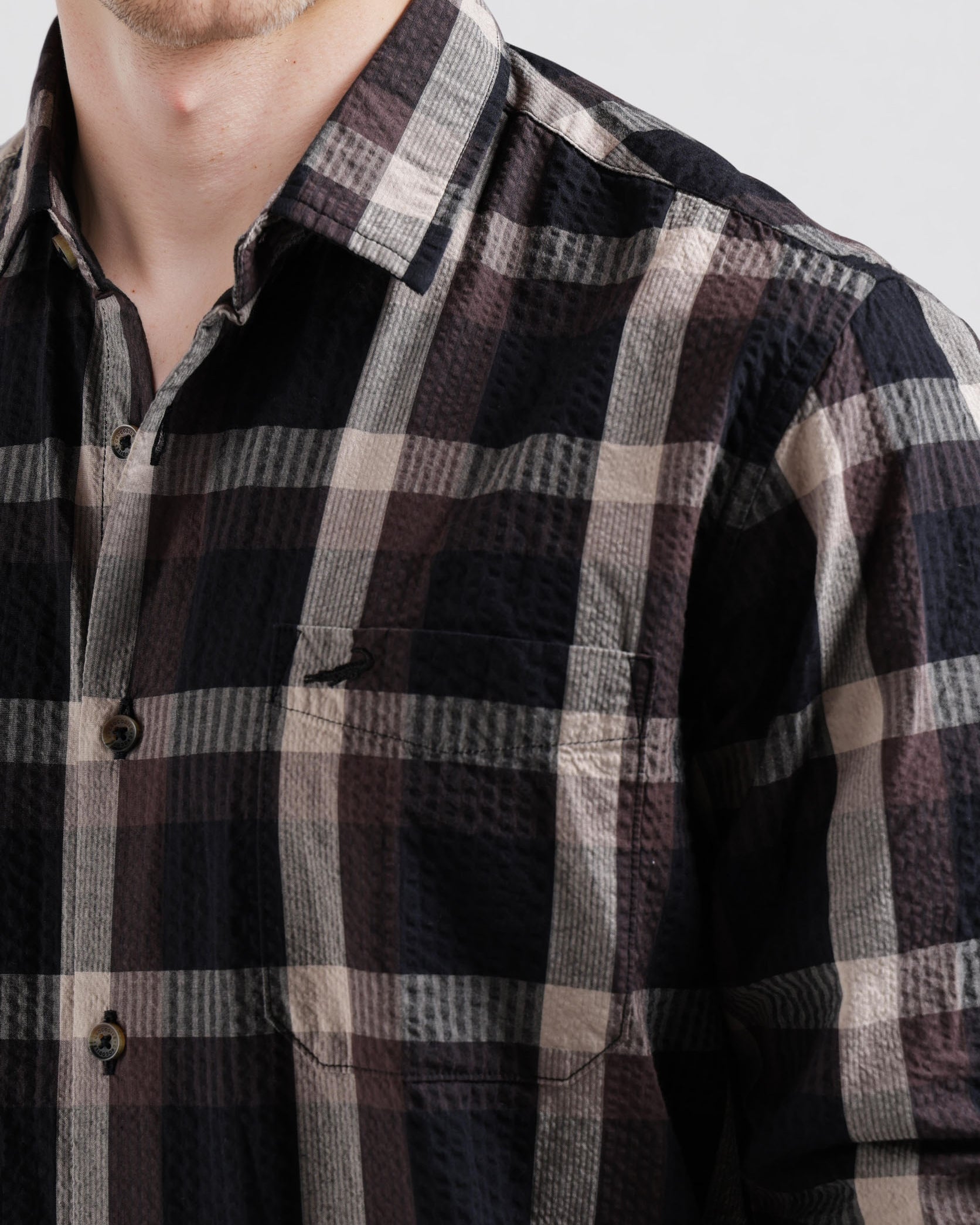 Close-up of a person wearing a plaid shirt with a neutral background