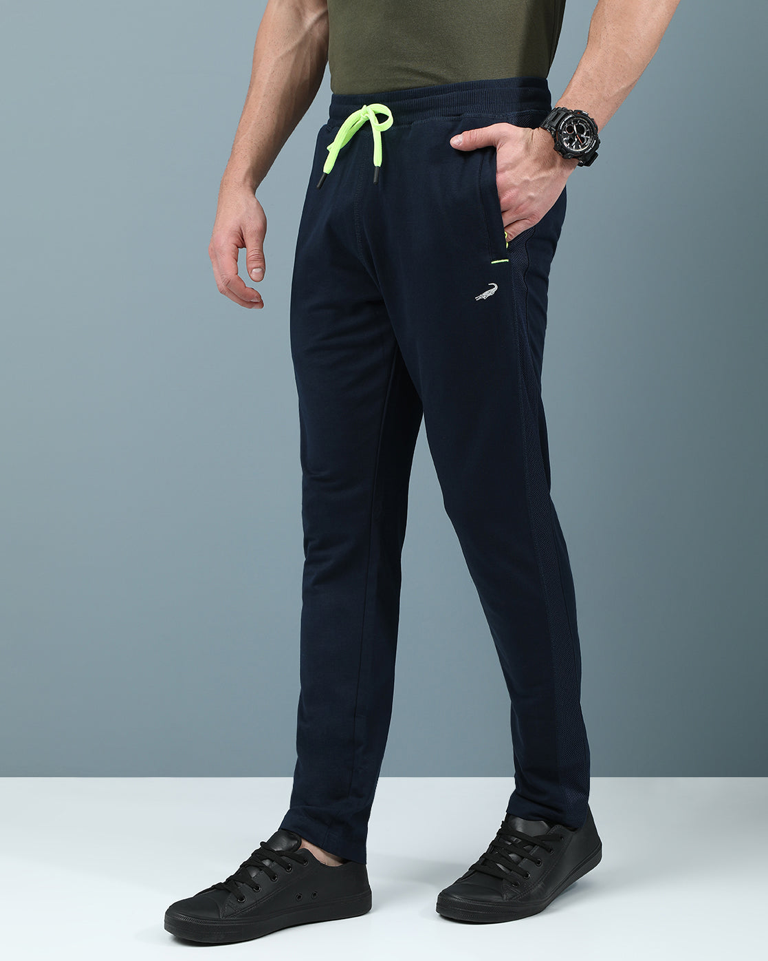 Man wearing a navy slim fit track pants in flexible navy on a light gray background