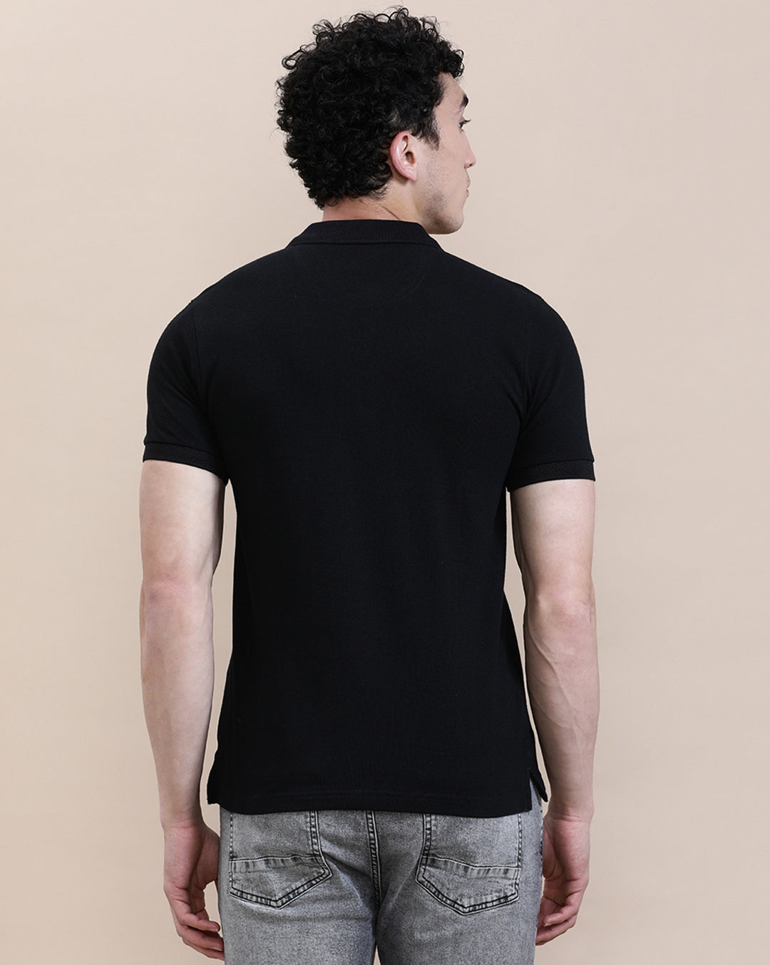 Man wearing a black casual solid black polo t shirt with pocket with casual styling on a gray background