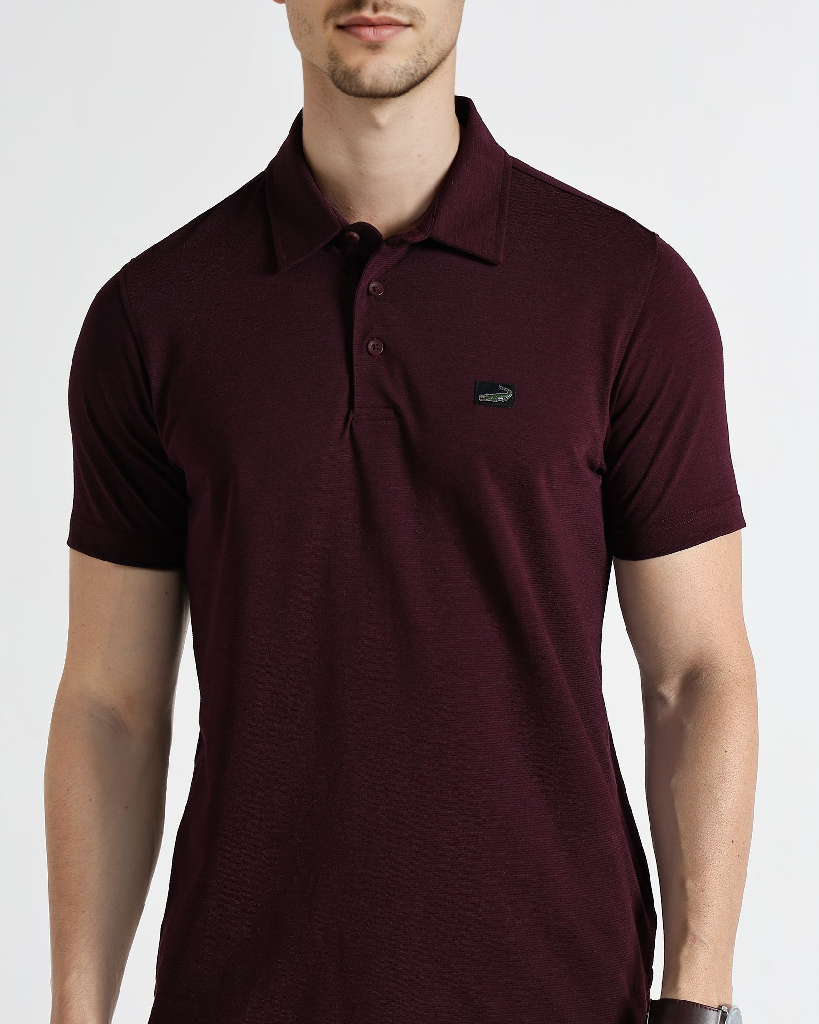 Man wearing a maroon polo shirt with a logo on a white background