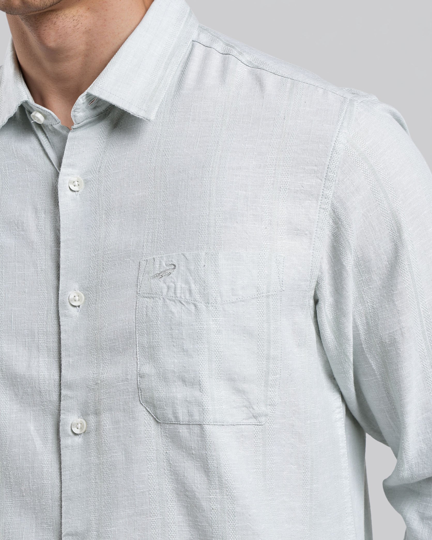 Light gray button-up shirt worn by a person on a plain background