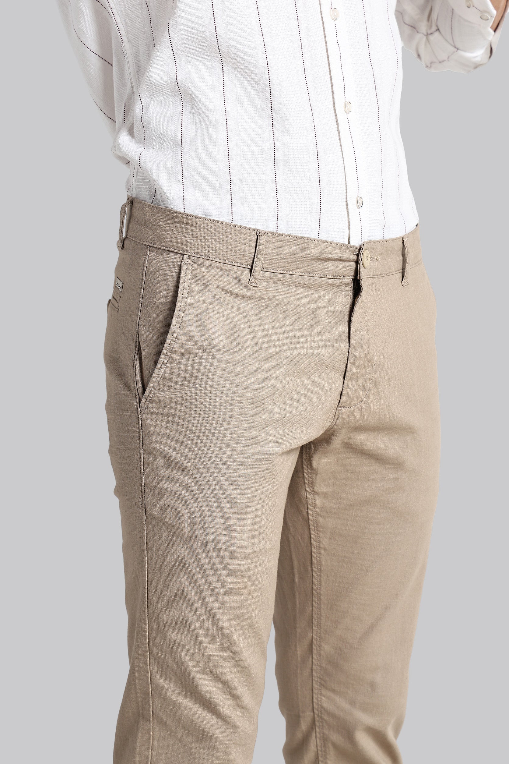 Beige pants worn with a white shirt on a plain background