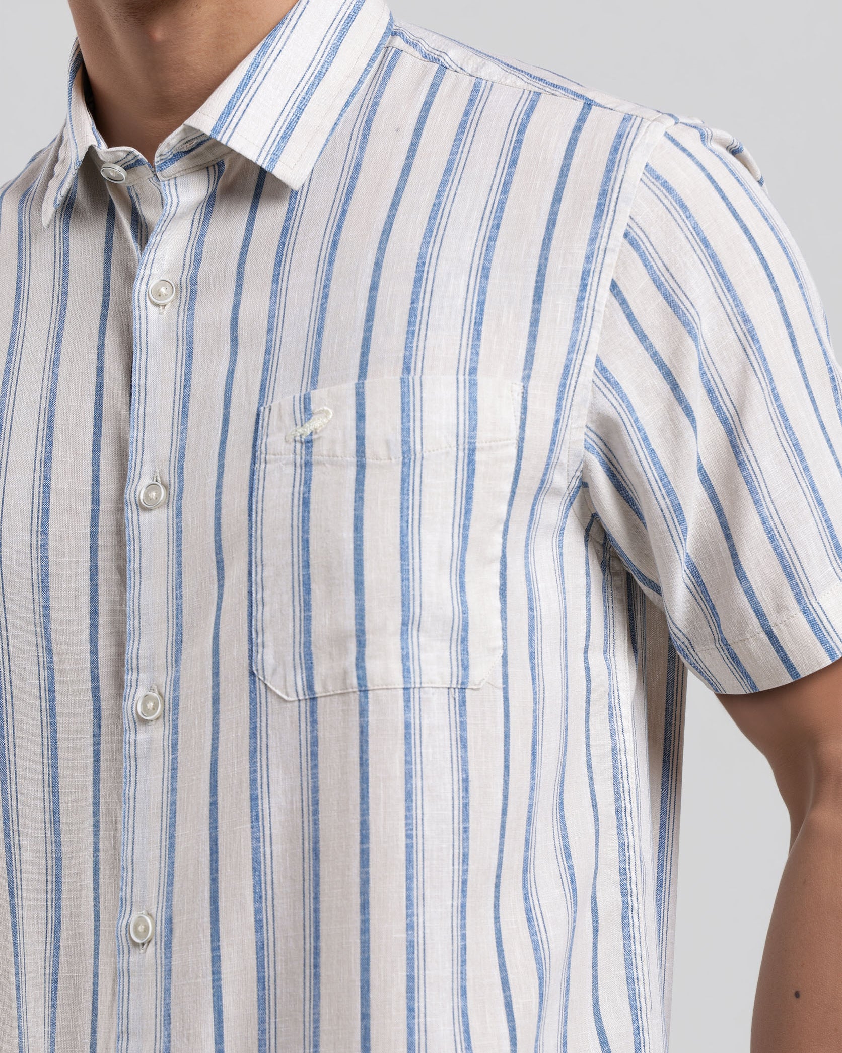 Man wearing a short-sleeve shirt with blue and white stripes on a plain background