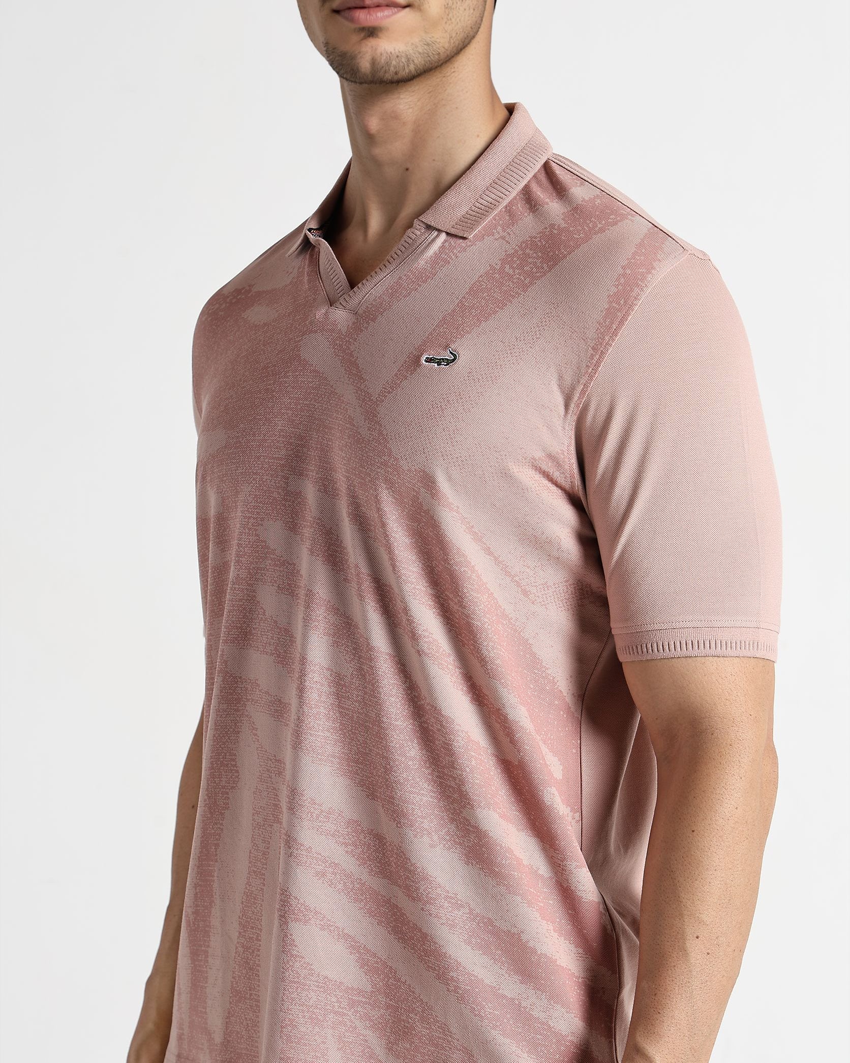 Man wearing a pink polo shirt with a brand logo on a white background