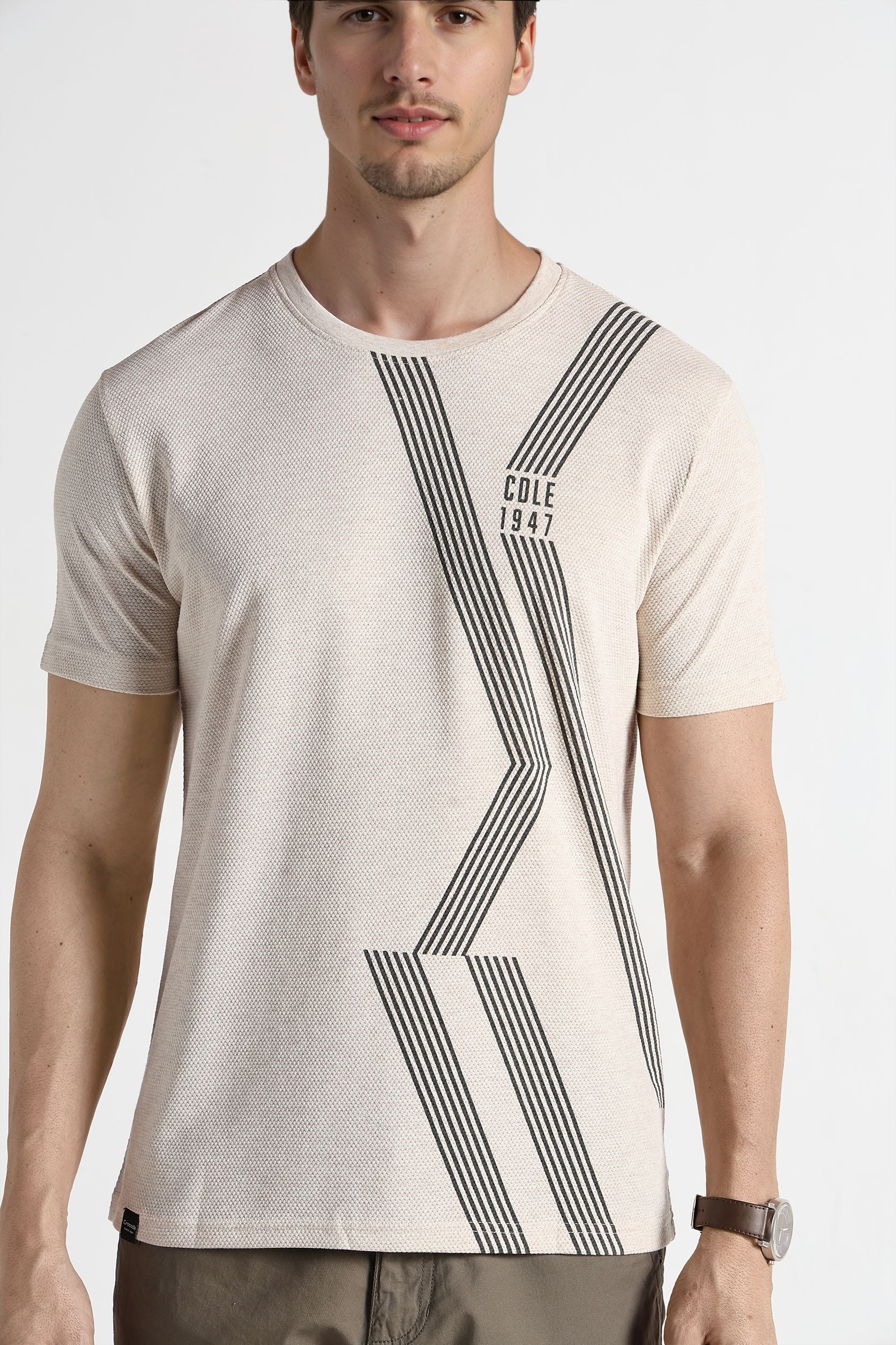 Man wearing a beige t-shirt with black geometric design on a white background