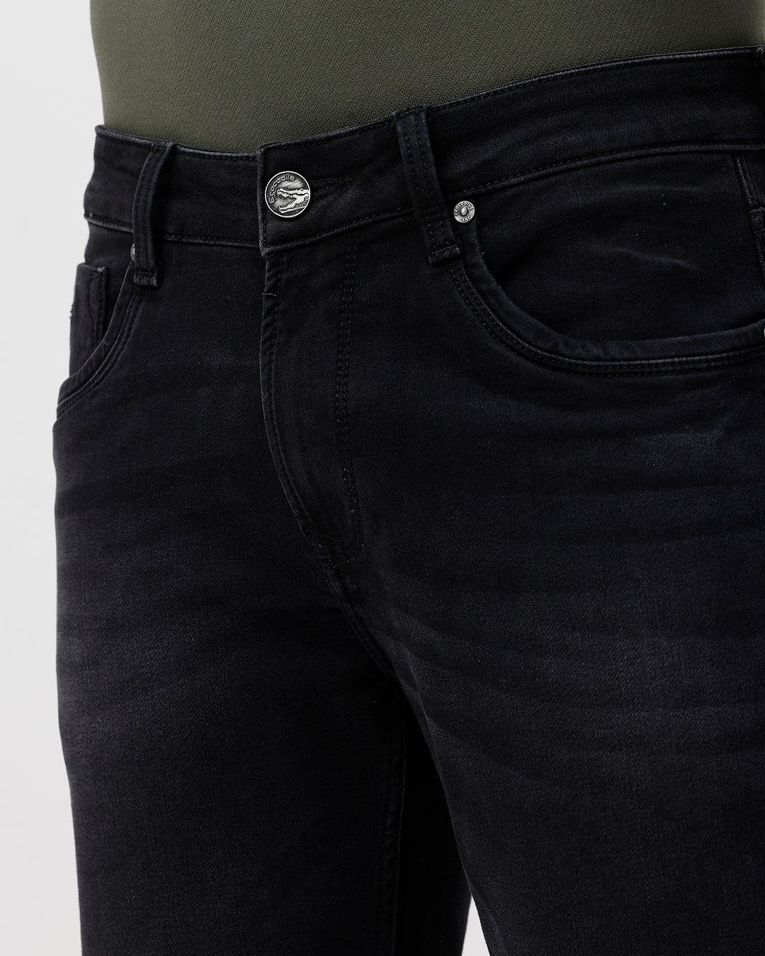 Close-up of black jeans with a visible brand button on a white background