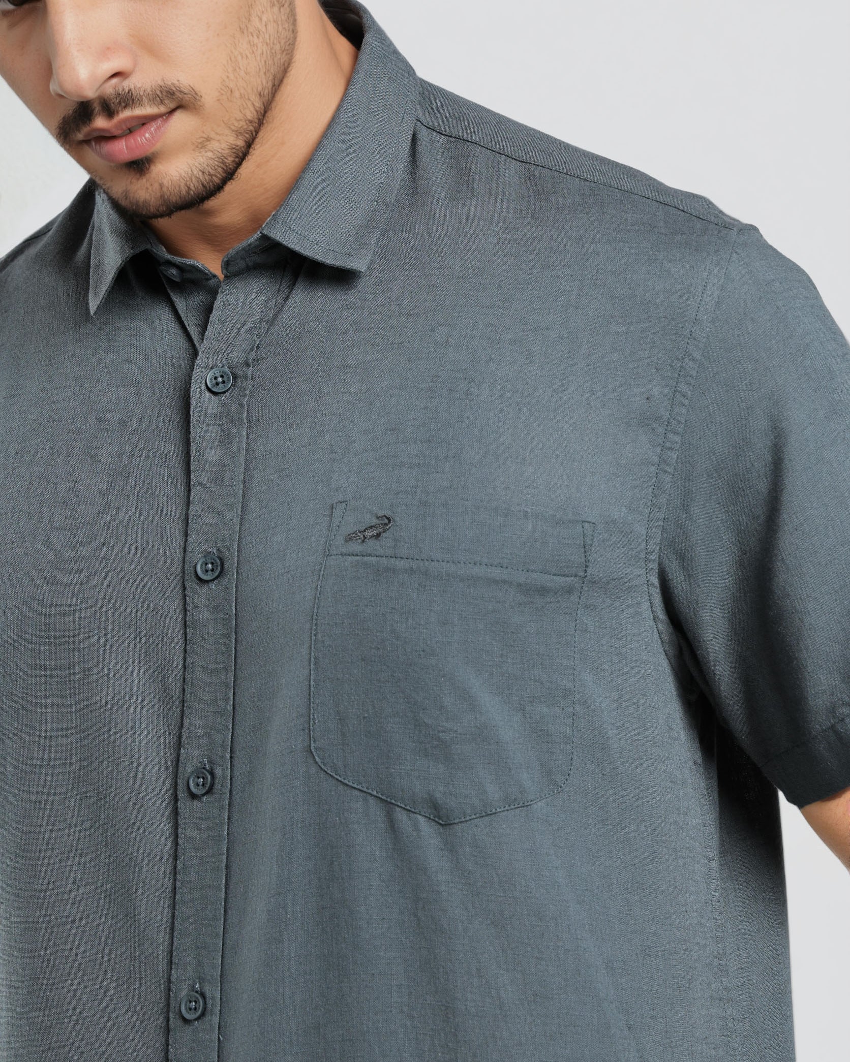 Man wearing a gray short-sleeve shirt with a pocket on a white background