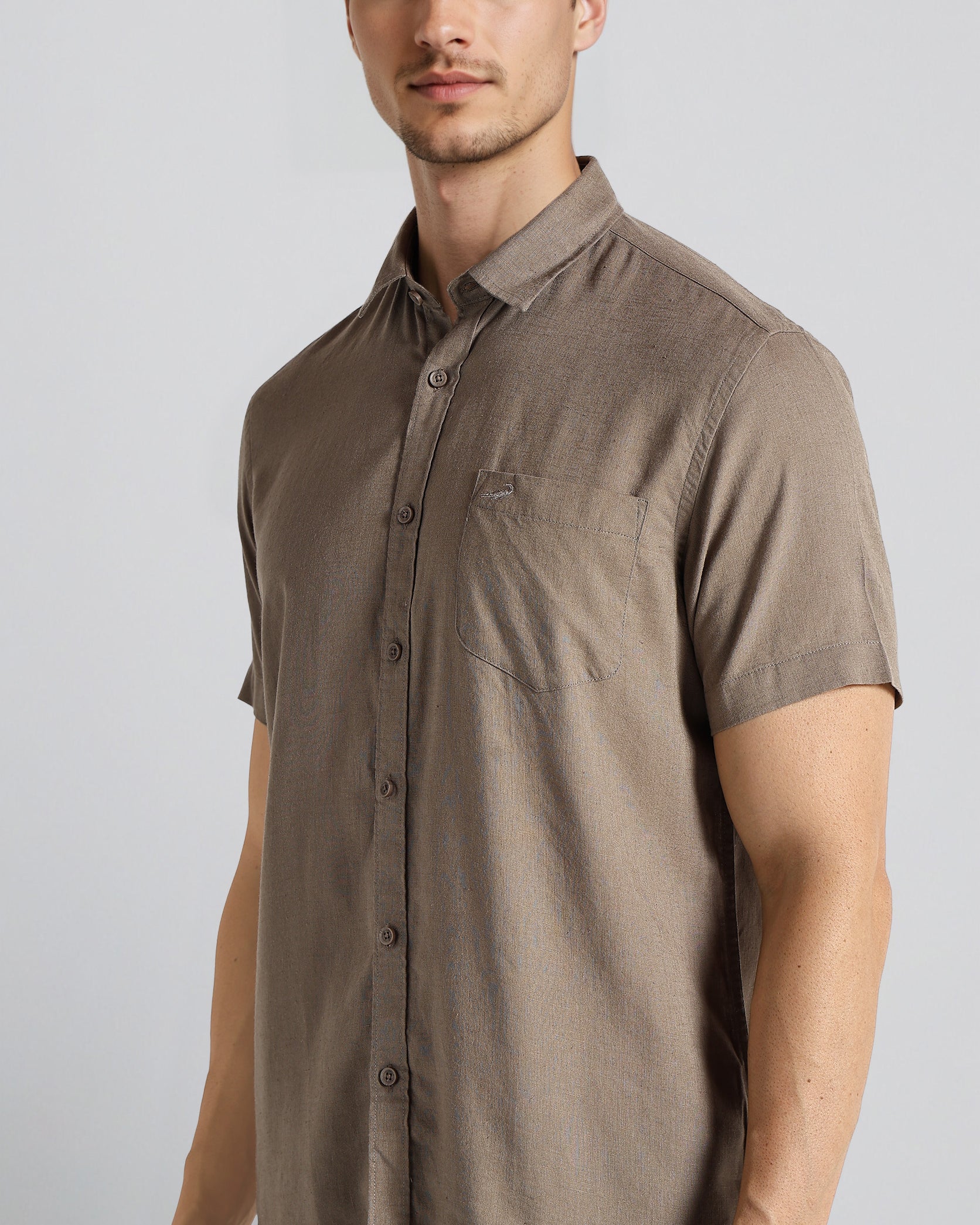 Man wearing a brown short-sleeve shirt against a white background