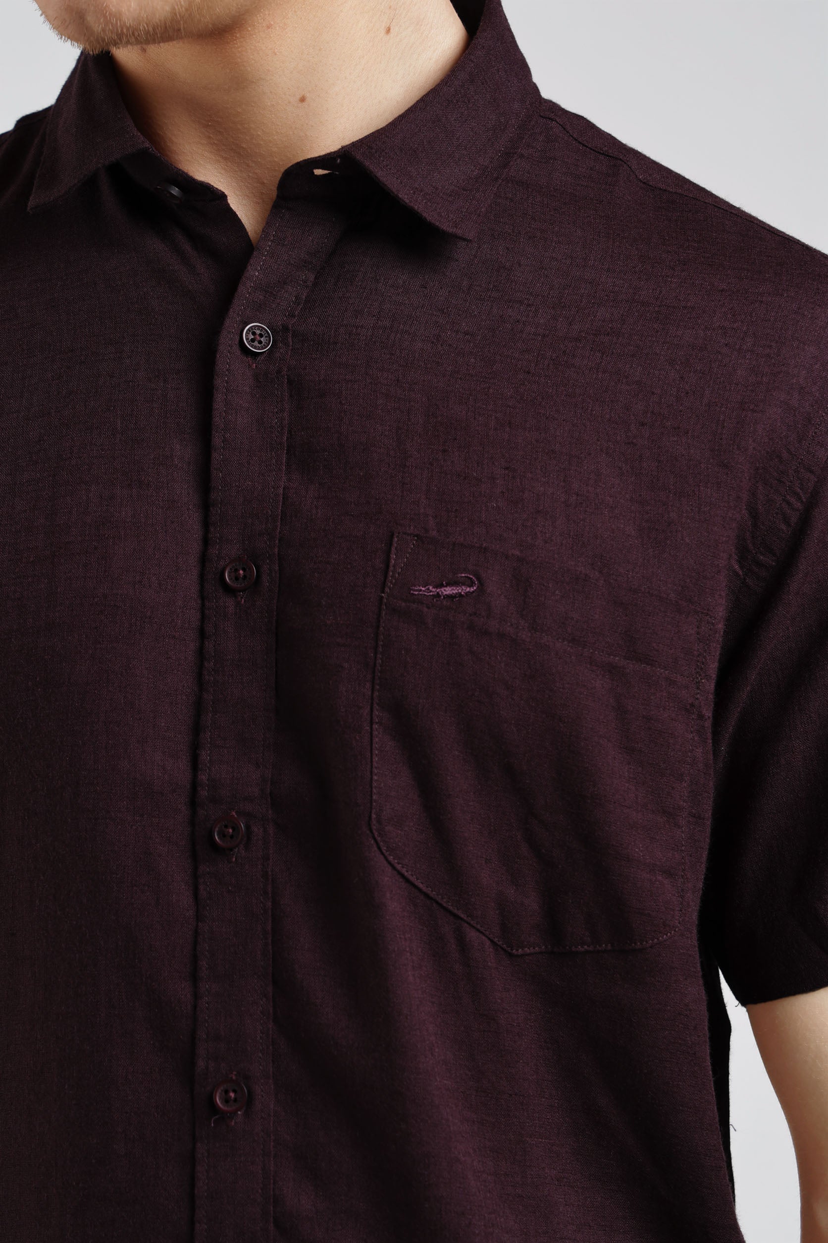 Close-up of a maroon button-up shirt with a pocket on a plain background