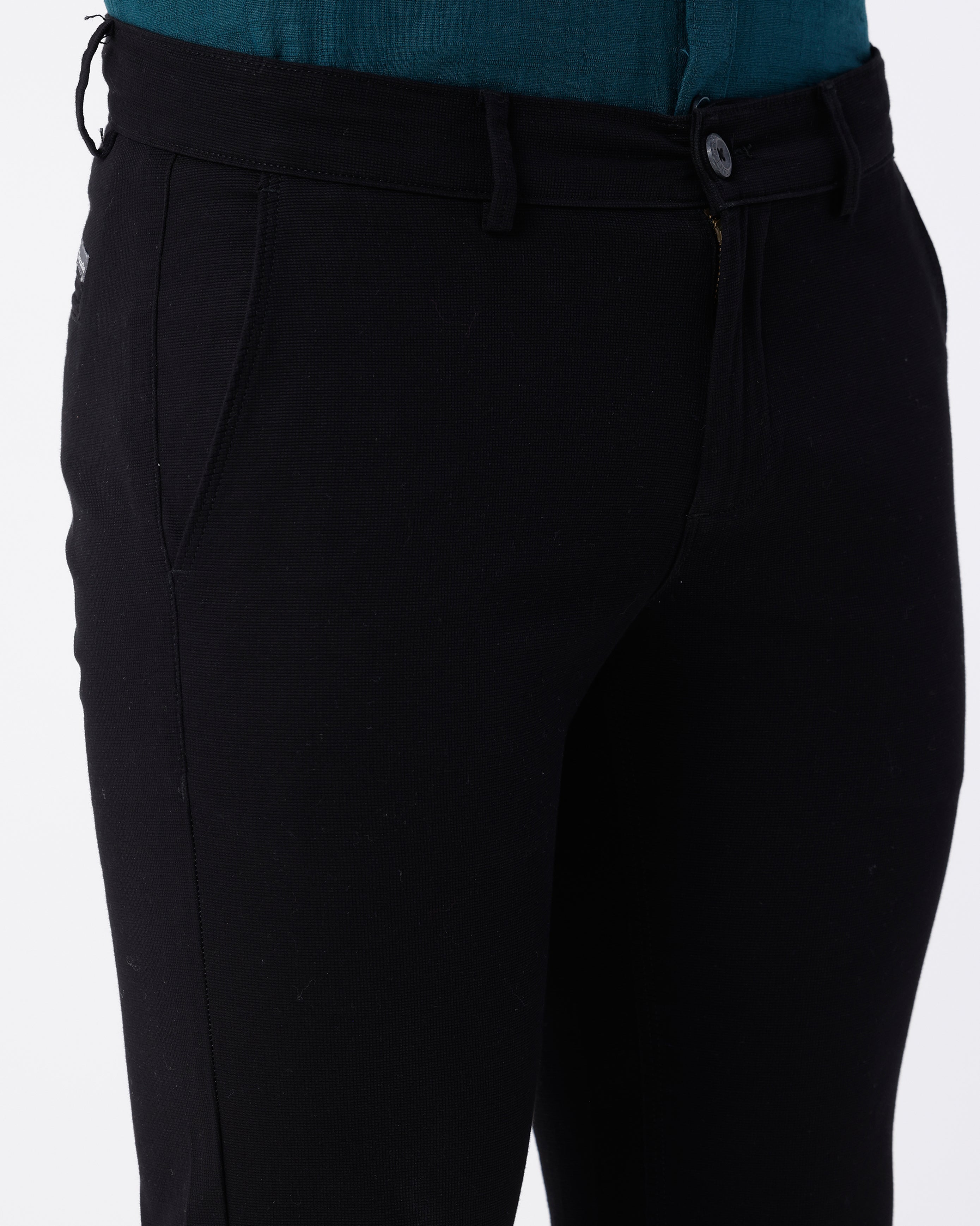 Woman wearing a black textured essential chinos in black on a light gray background