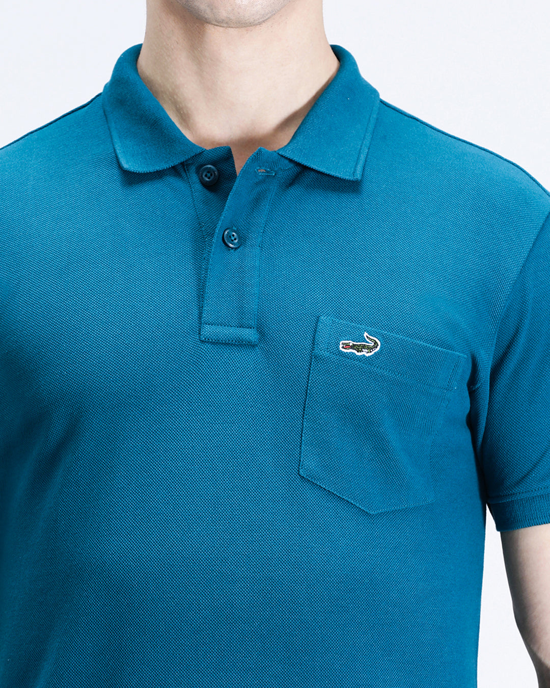 Man wearing a blue blue coral solid polo t shirt with casual styling on a gray background