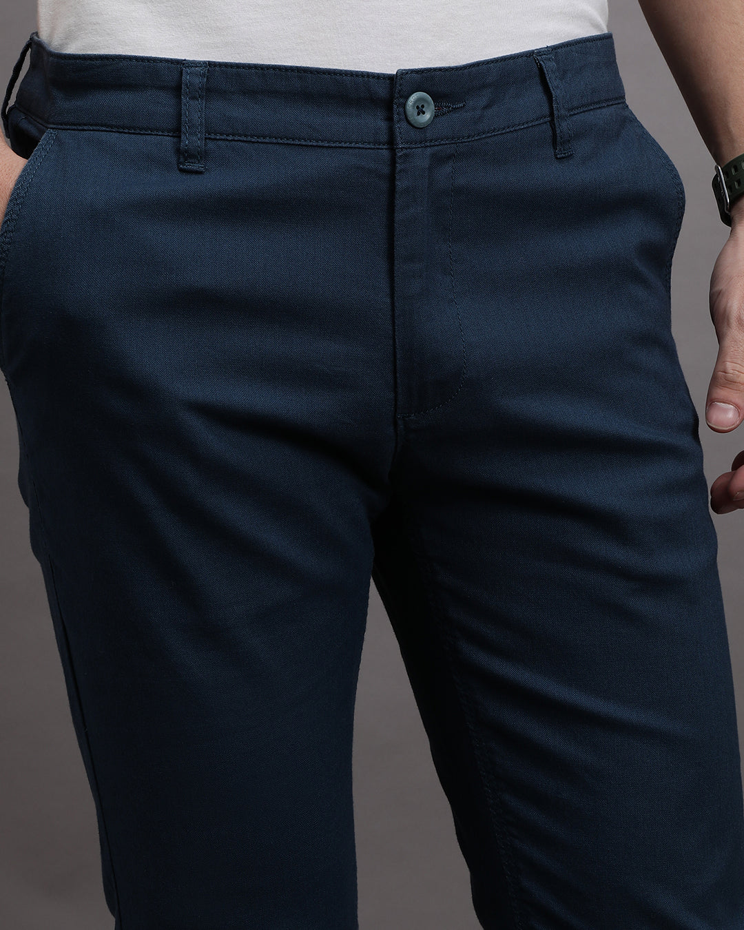 Man wearing a navy solid slim fit casual navy trouser on a light gray background