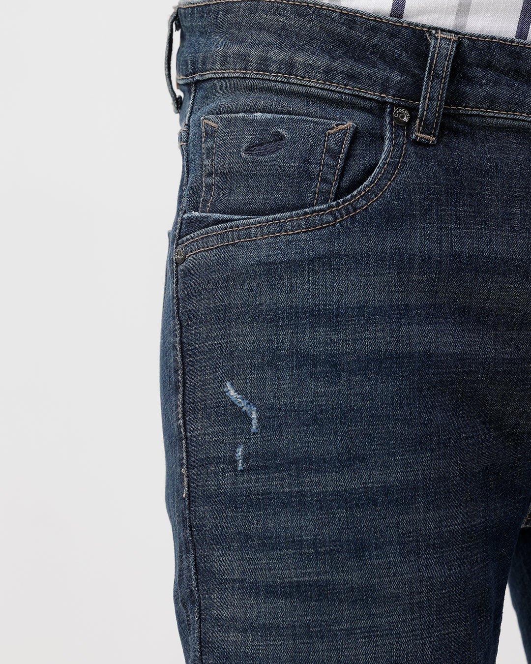Close-up of dark blue jeans with a visible brand logo on a white background
