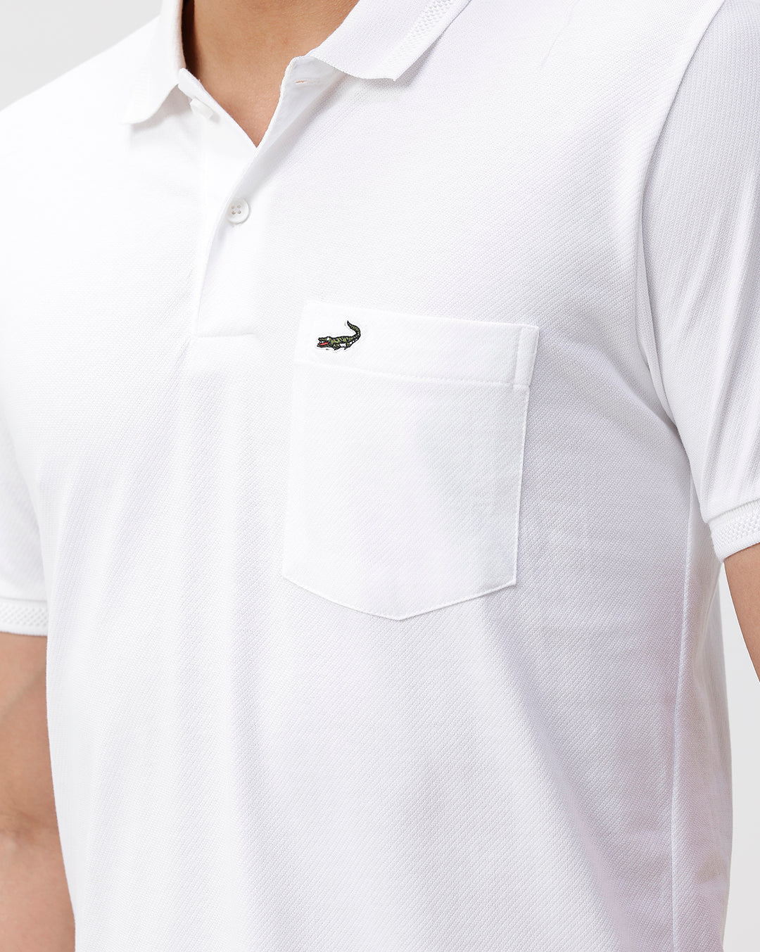 Man wearing a white solid white slim fit polo t shirt with casual styling on a gray background