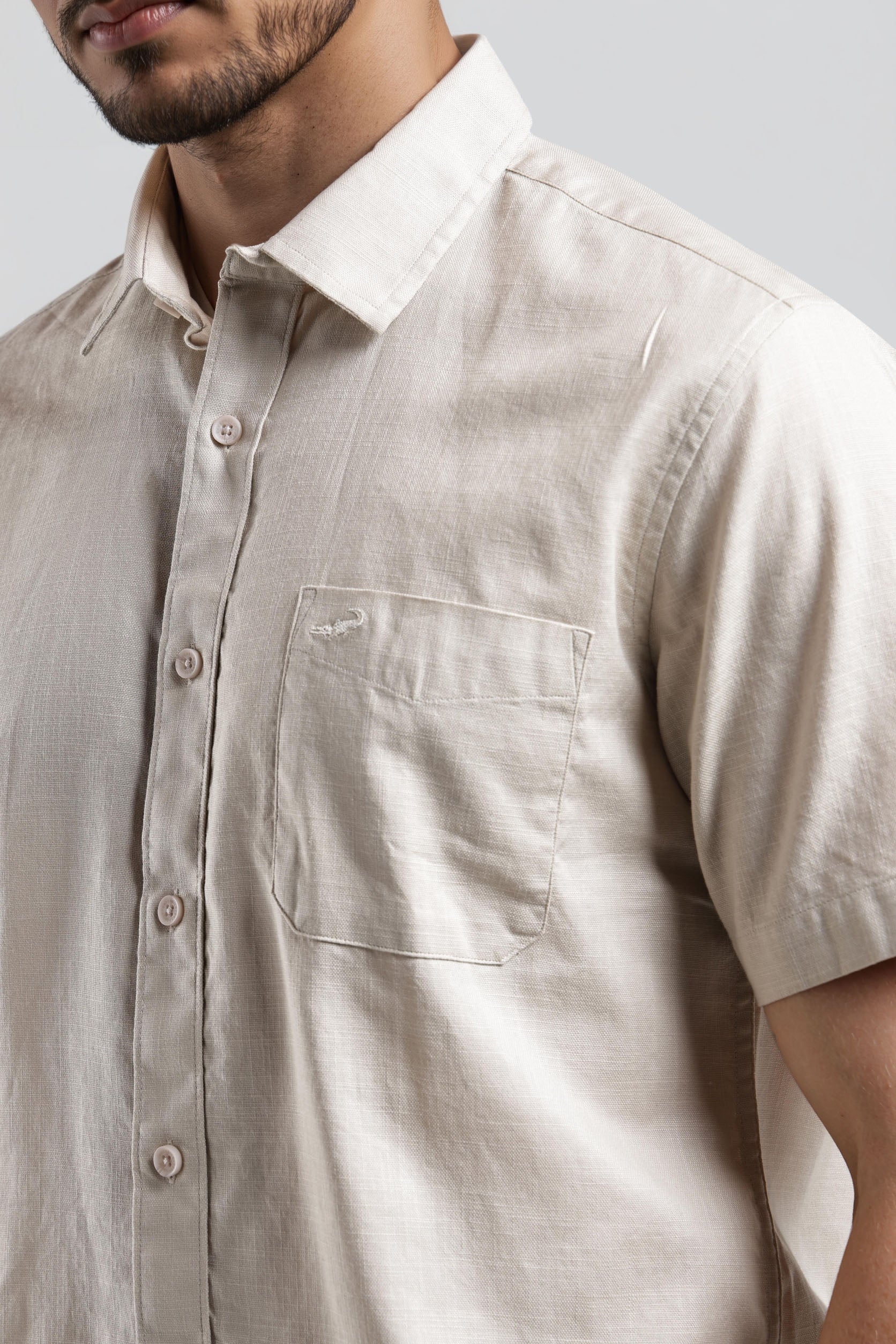 Beige short-sleeve shirt worn by a person on a plain background