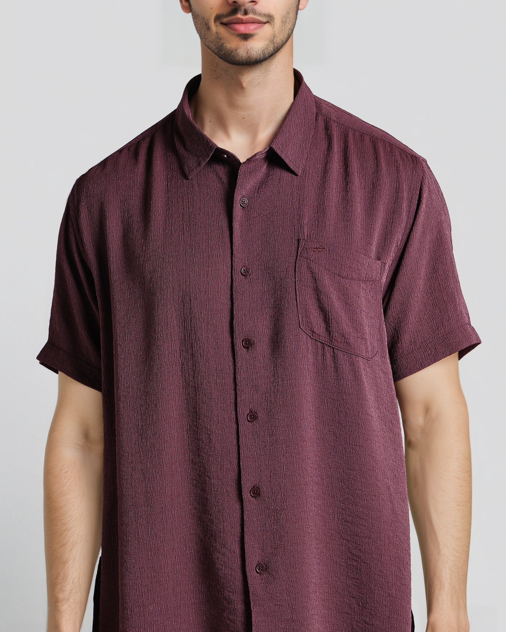 Man wearing a maroon short-sleeve shirt against a plain background