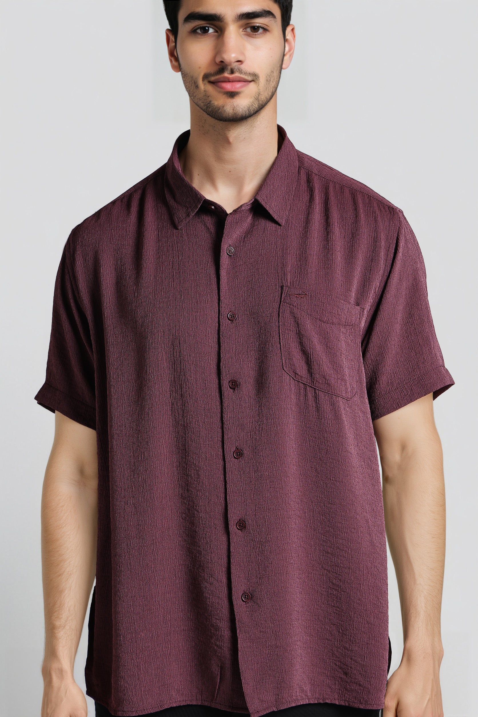 Man wearing a maroon short-sleeve shirt against a plain background