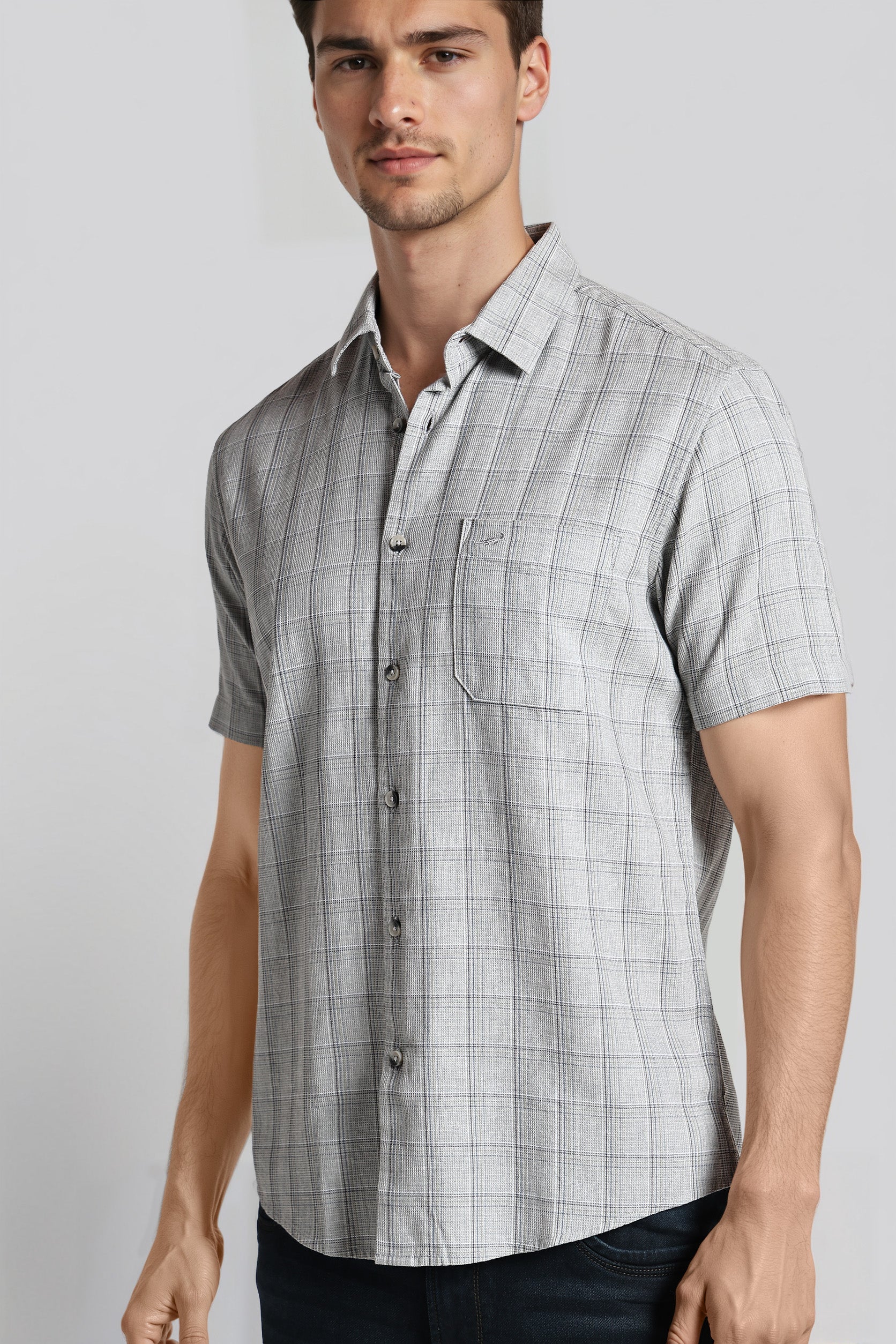 Man wearing a gray checkered short-sleeve shirt against a plain background