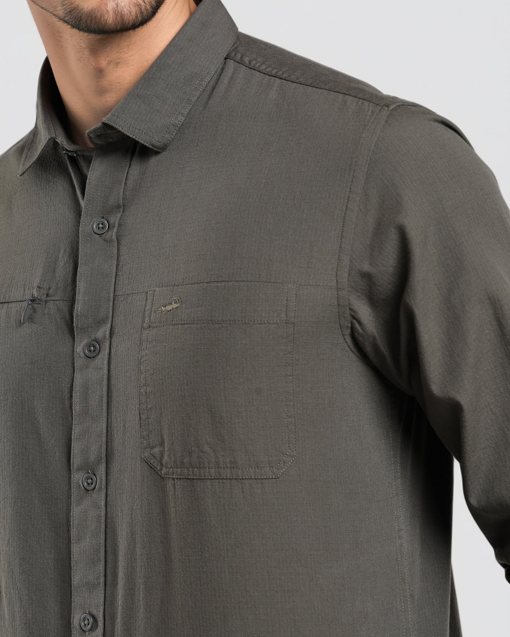 Man wearing a dark gray button-up shirt on a light gray background