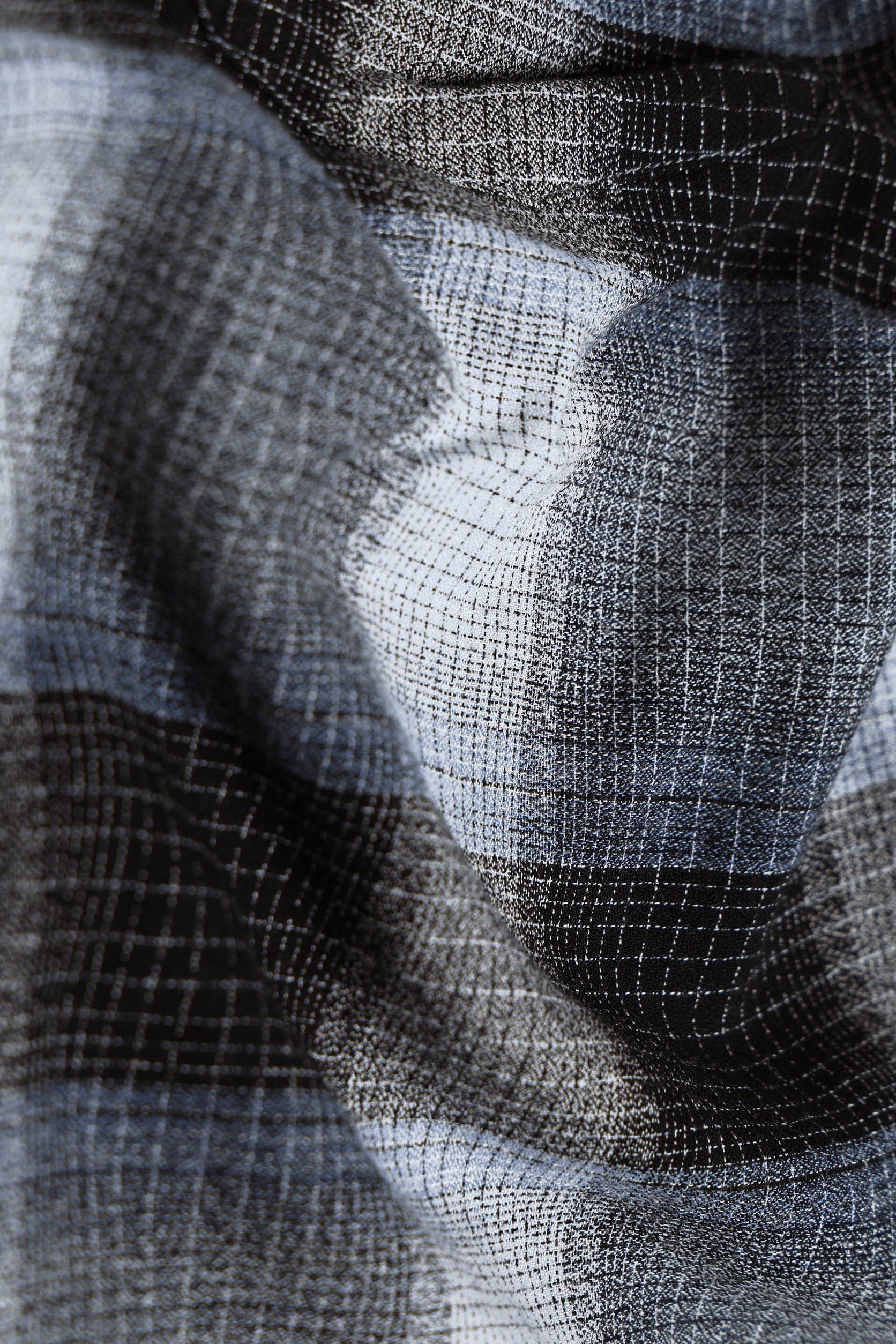 Close-up of textured fabric with a checkered pattern in black, white, and gray.