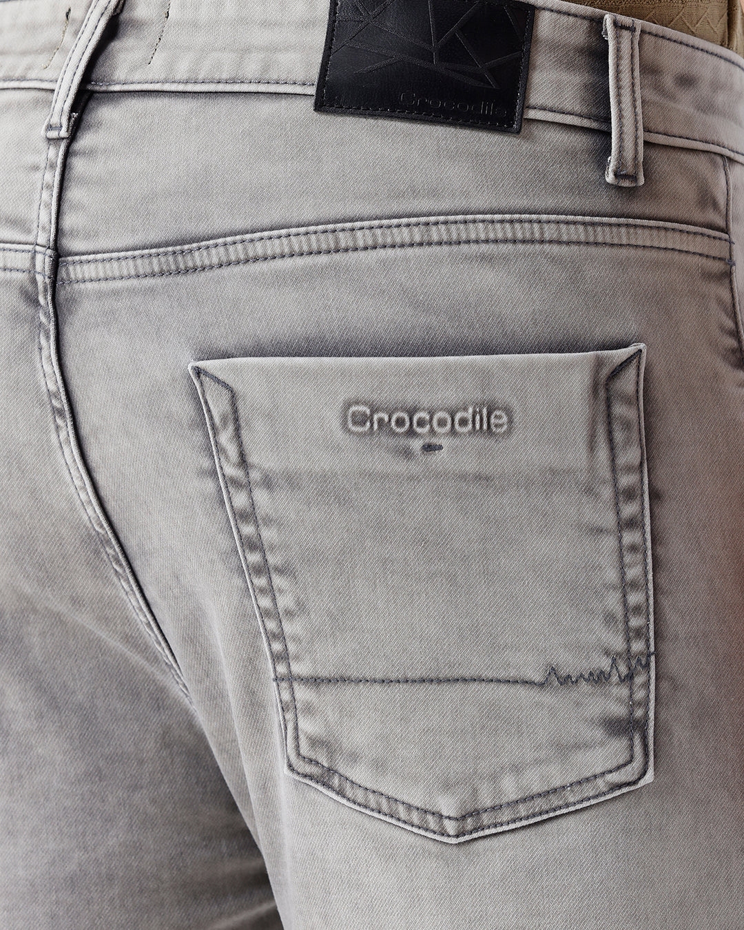 Man wearing a grey light grey knit slim fit jeans on a light gray background