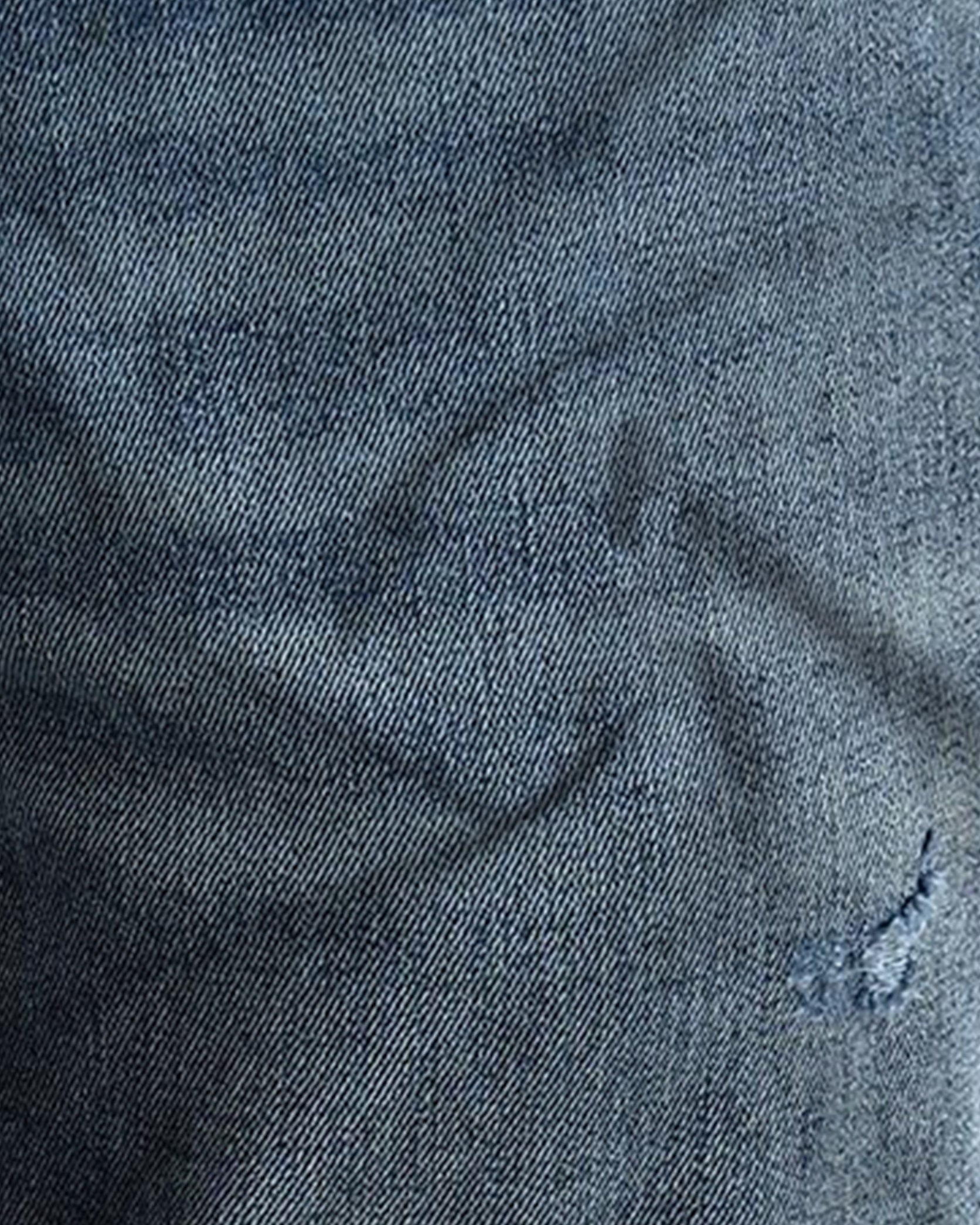 Close-up of dark blue denim fabric with texture and slight wear.