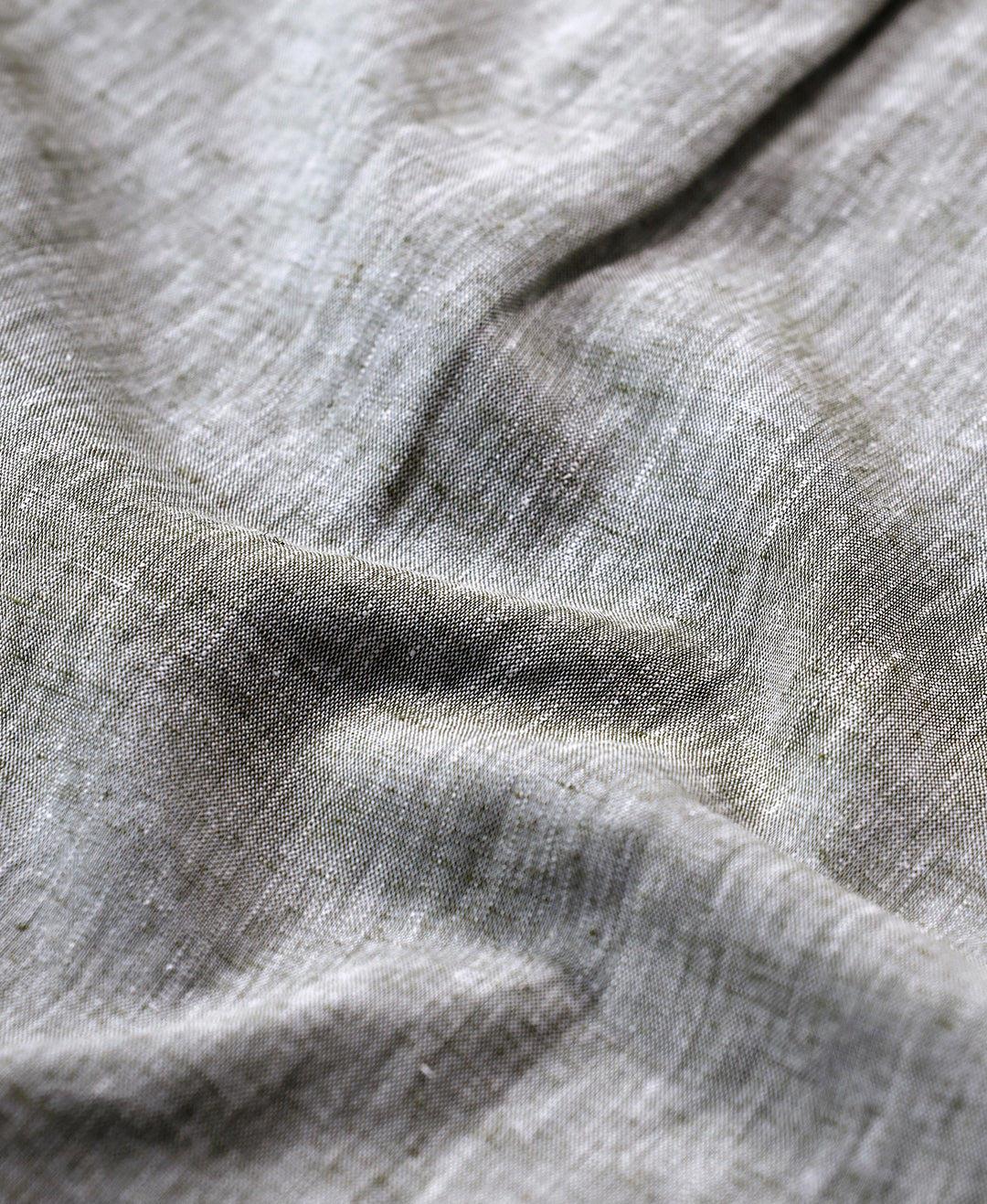 Man wearing a green premium tensil linen shirt dark green on a light gray background