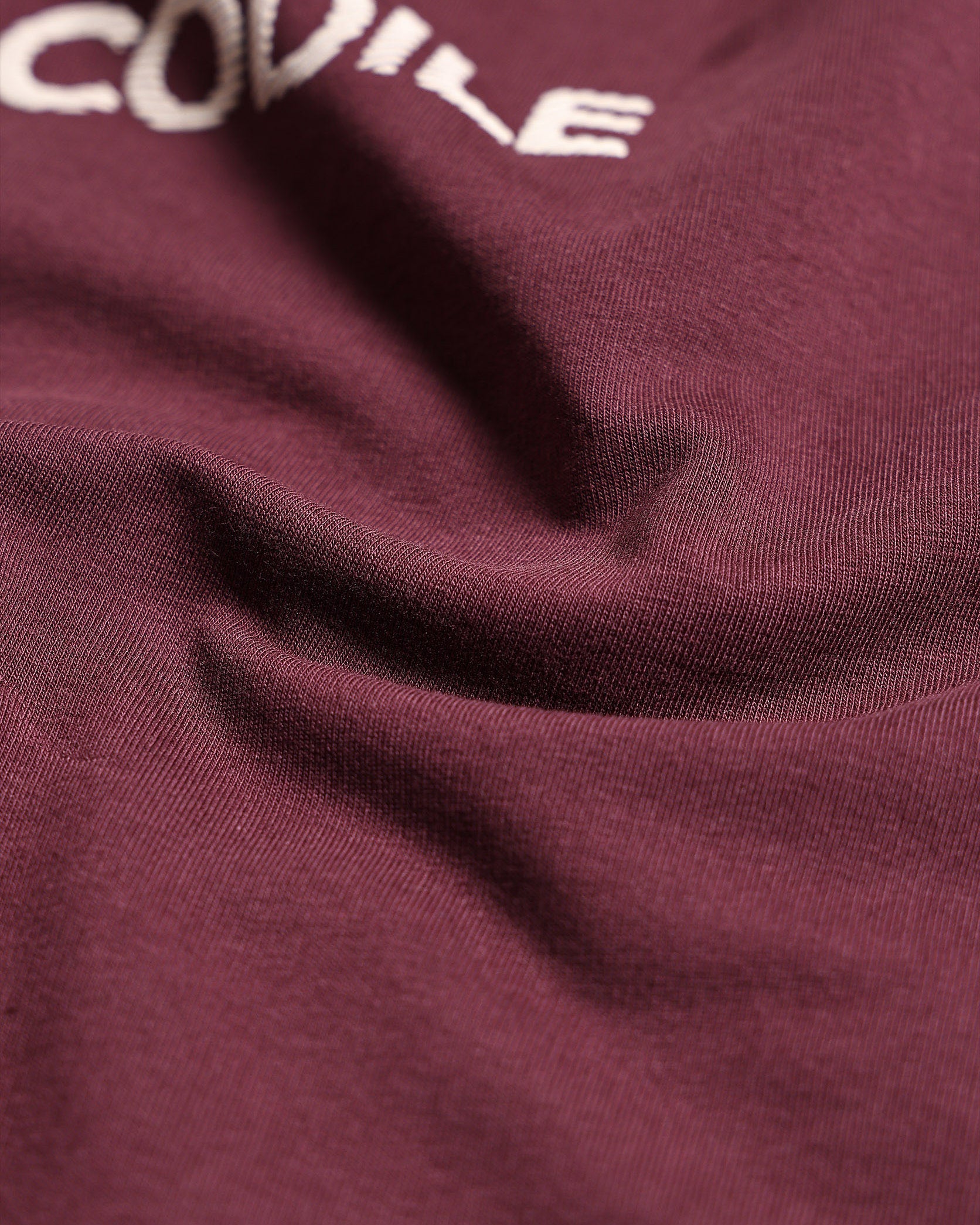 Close-up of a maroon fabric with 'CODILE' embroidered in white.