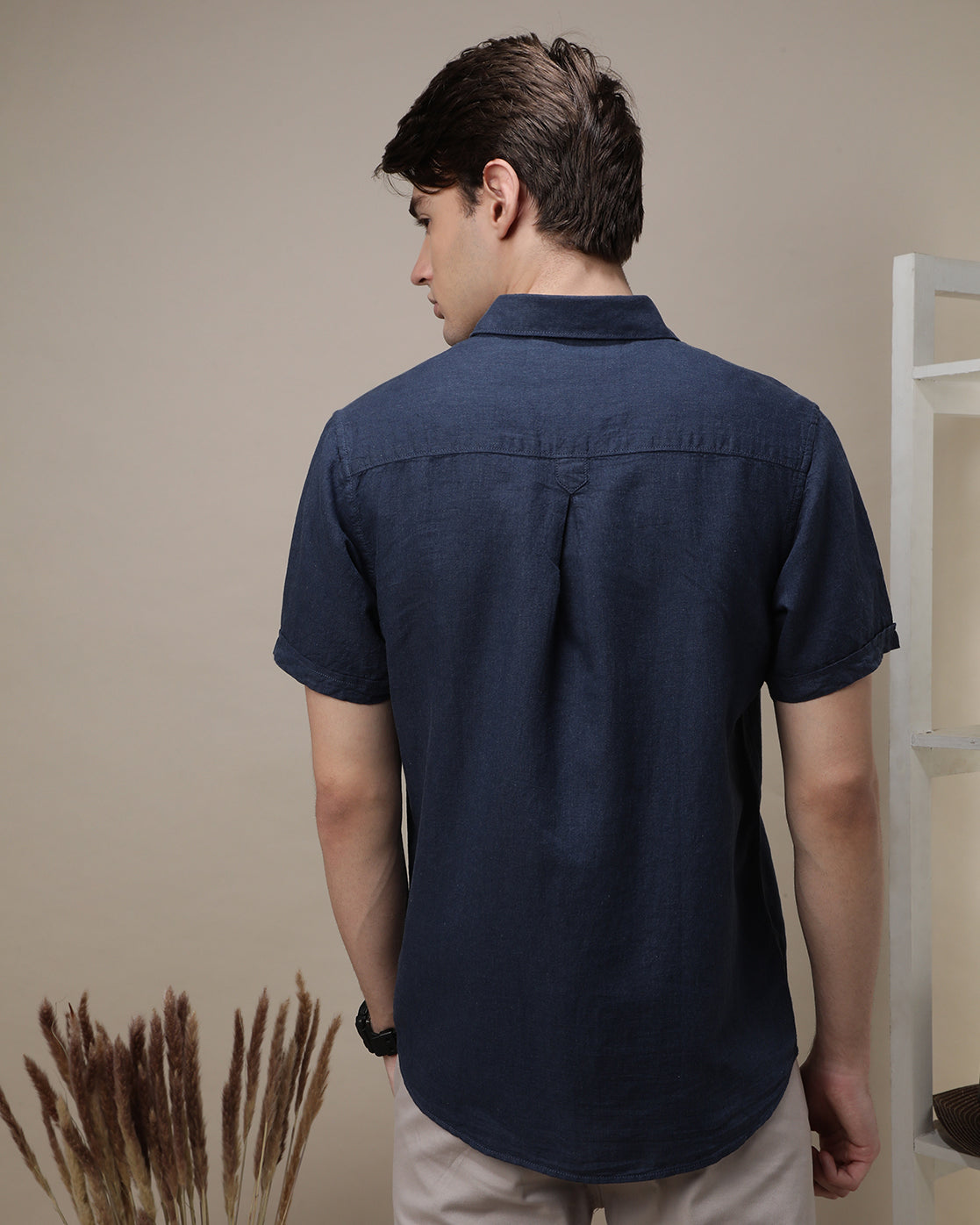Man wearing a navy navy solid half sleeve linen shirt on a light gray background
