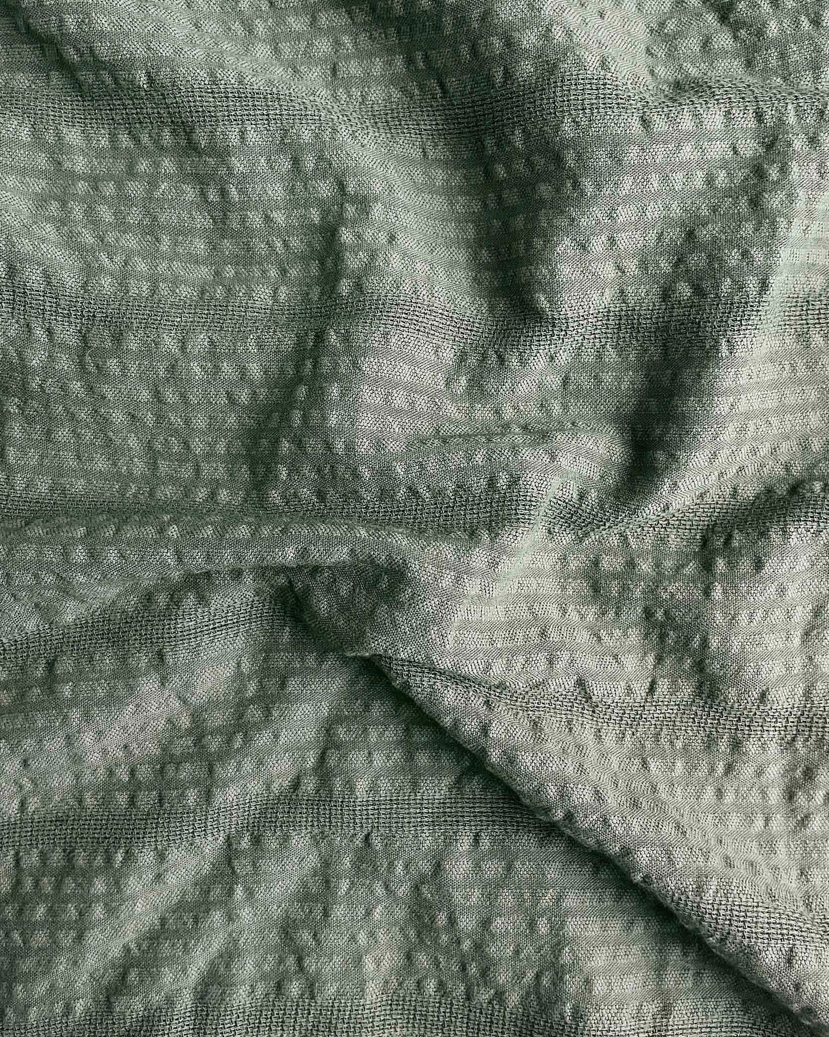 Close-up of textured green fabric with a subtle pattern
