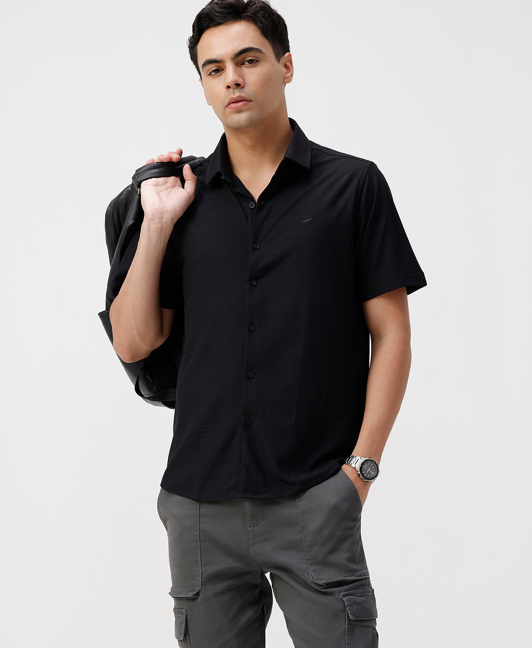 Man wearing a black solid black cotton shirt with casual styling on a gray background