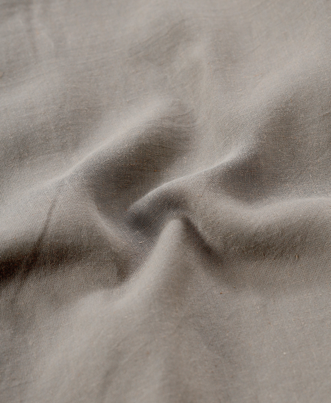 Man wearing a beige linen blend shirt in dark beige on a light gray background