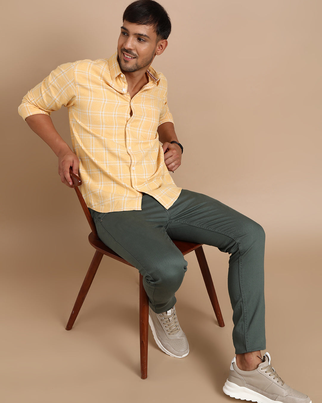 Man wearing a yellow casual yellow checked full sleeve 100% cotton shirt with casual styling on a gray background