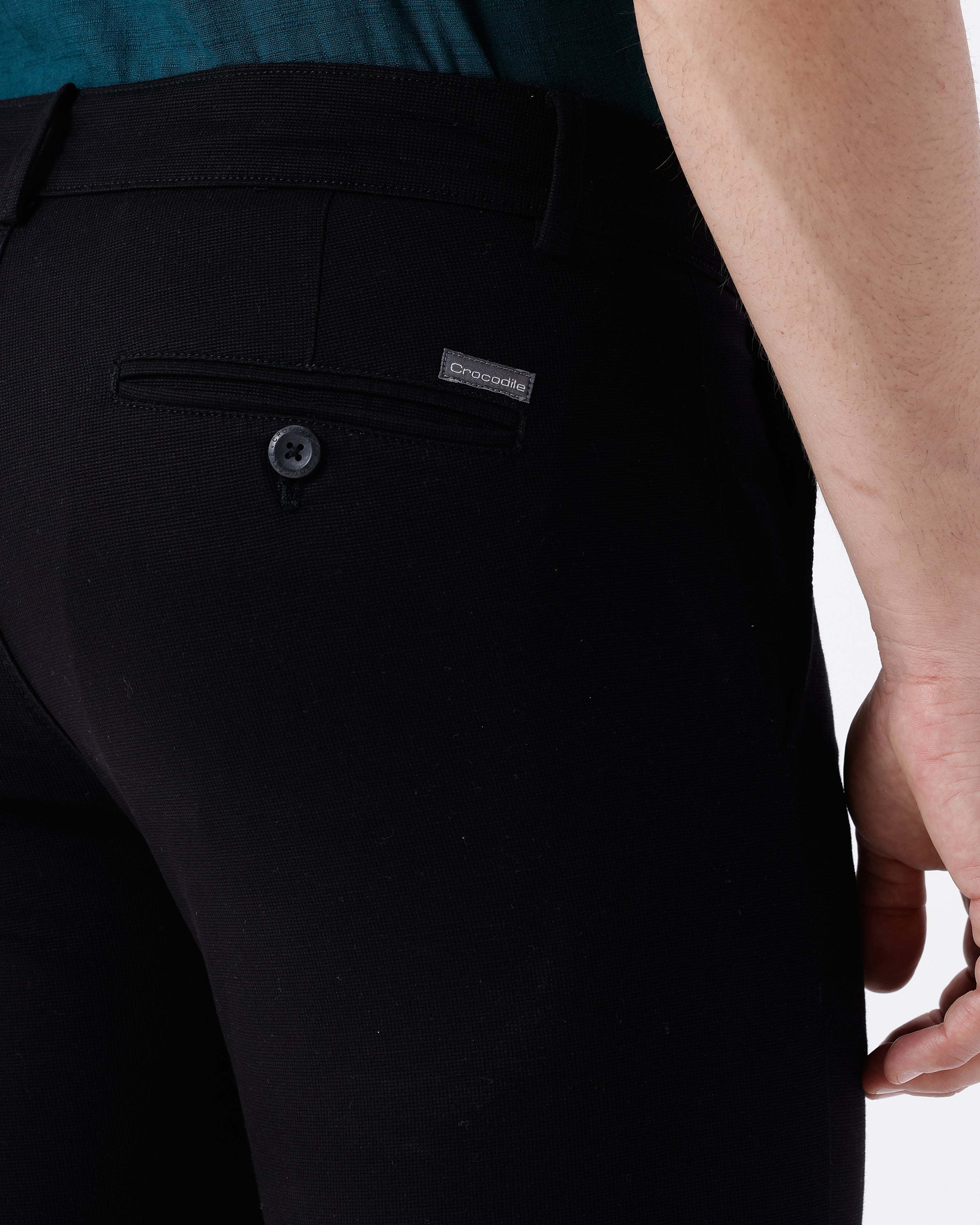 Woman wearing a black textured essential chinos in black on a light gray background