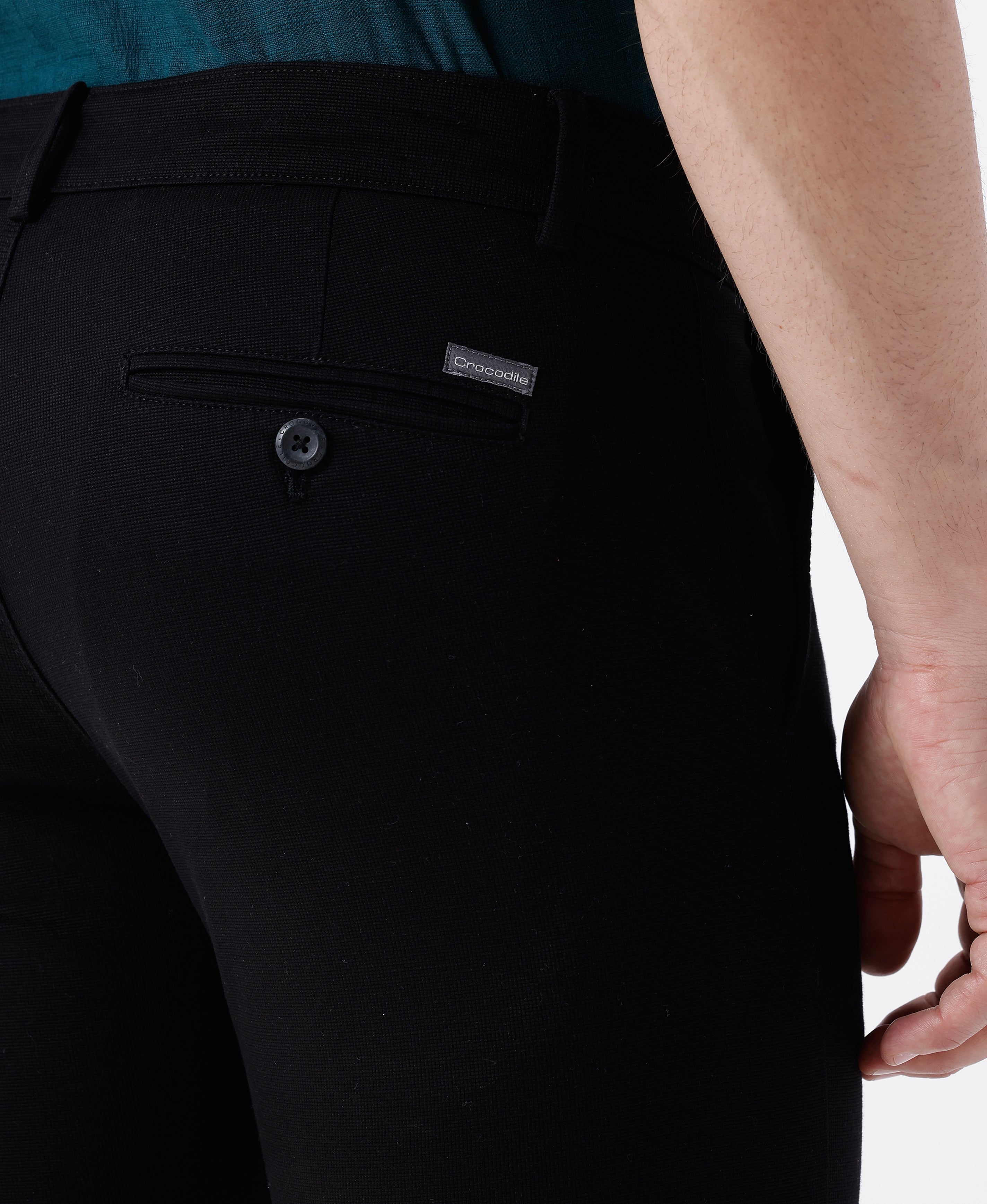 Woman wearing a black textured essential chinos in black on a light gray background