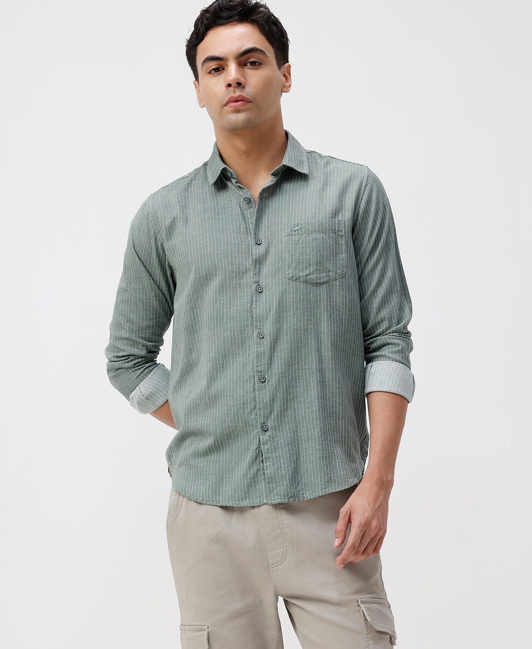 Man wearing a green checkered shirt and beige pants on a white background