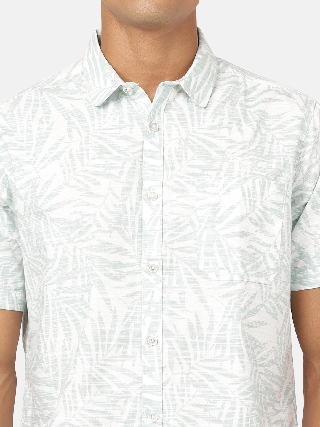 Man wearing a green sea green printed half sleeve 100% cotton shirt on a light gray background