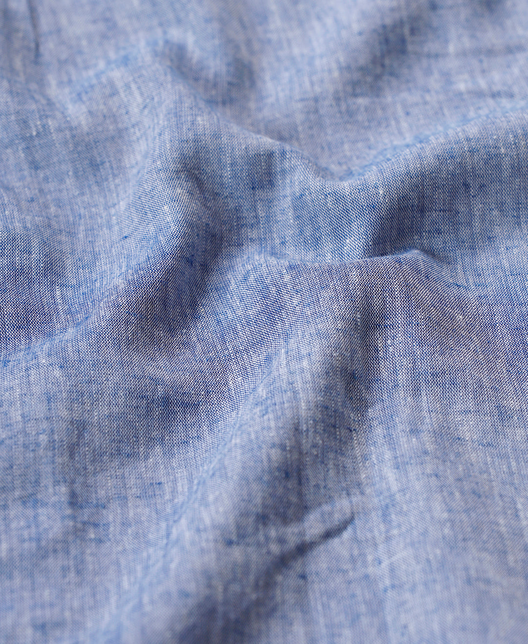 Man wearing a blue premium tensil linen shirt blue on a light gray background