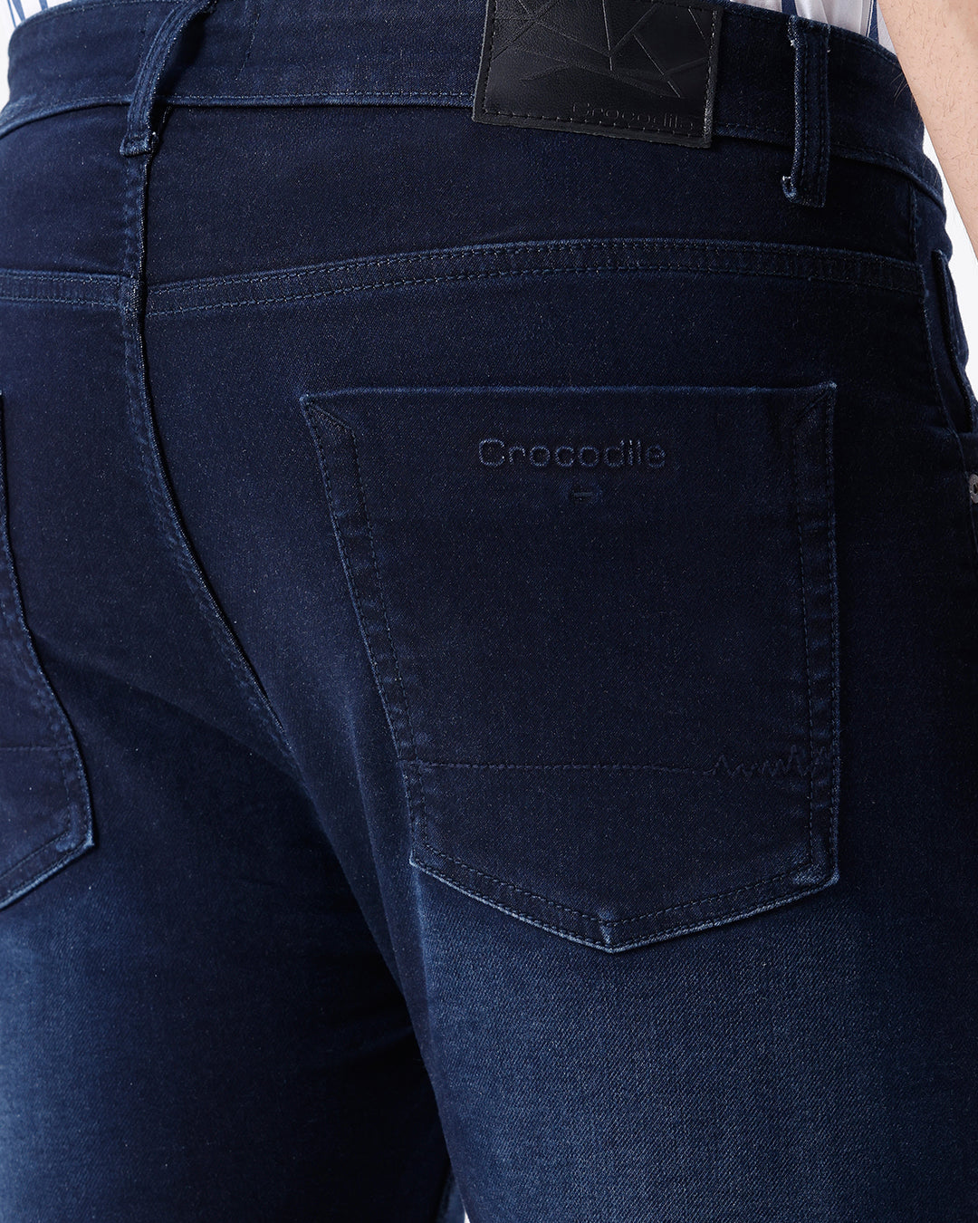 Man wearing a blue dark blue knit slim fit jeans with casual styling on a gray background