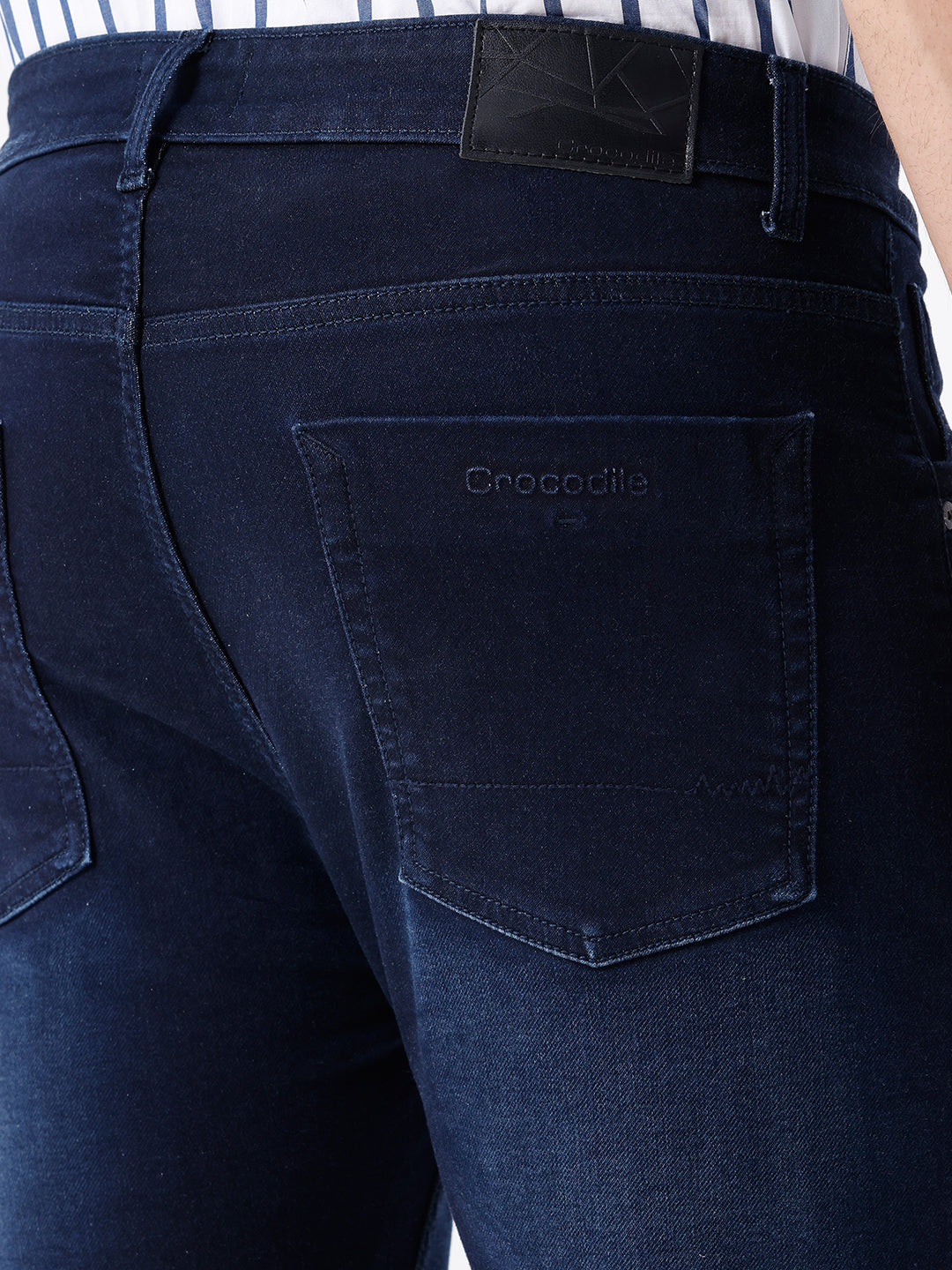 Man wearing a blue dark blue knit slim fit jeans with casual styling on a gray background